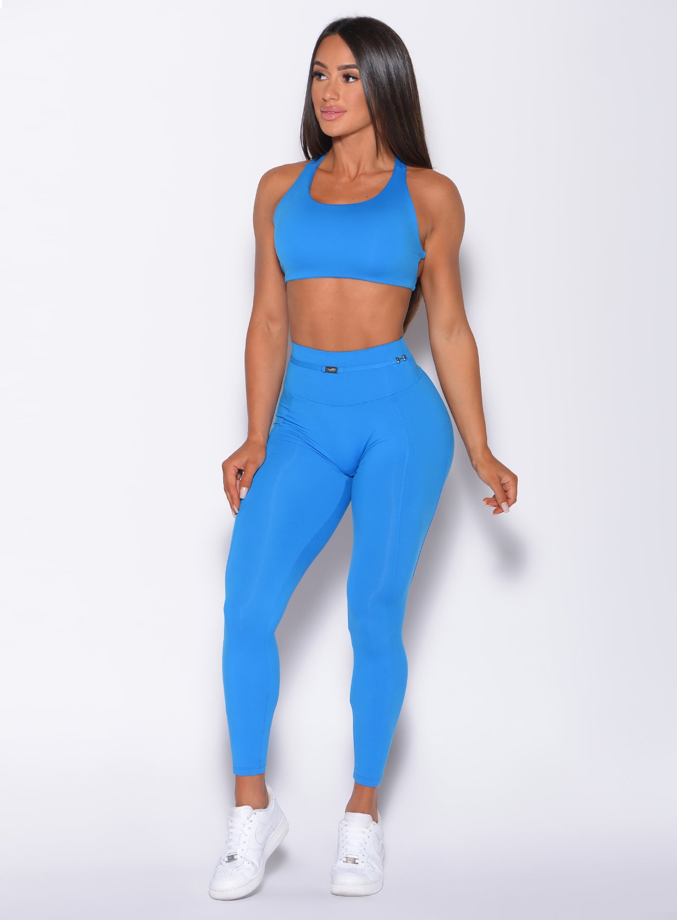 Front profile view of a model in our barbell leggings in crystal pop blue color and a matching bra 