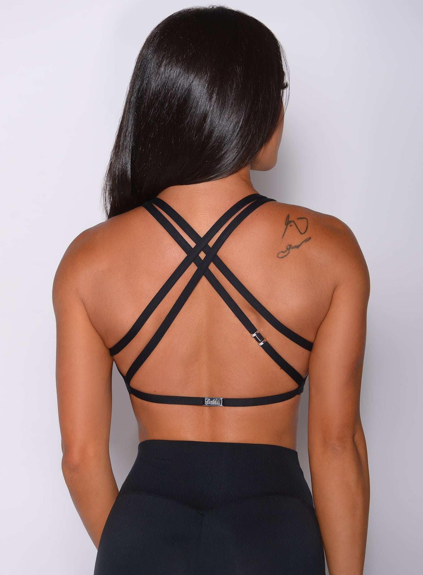 Zoomed in back profile view of a model in our black barbell sports bra and a matching leggings