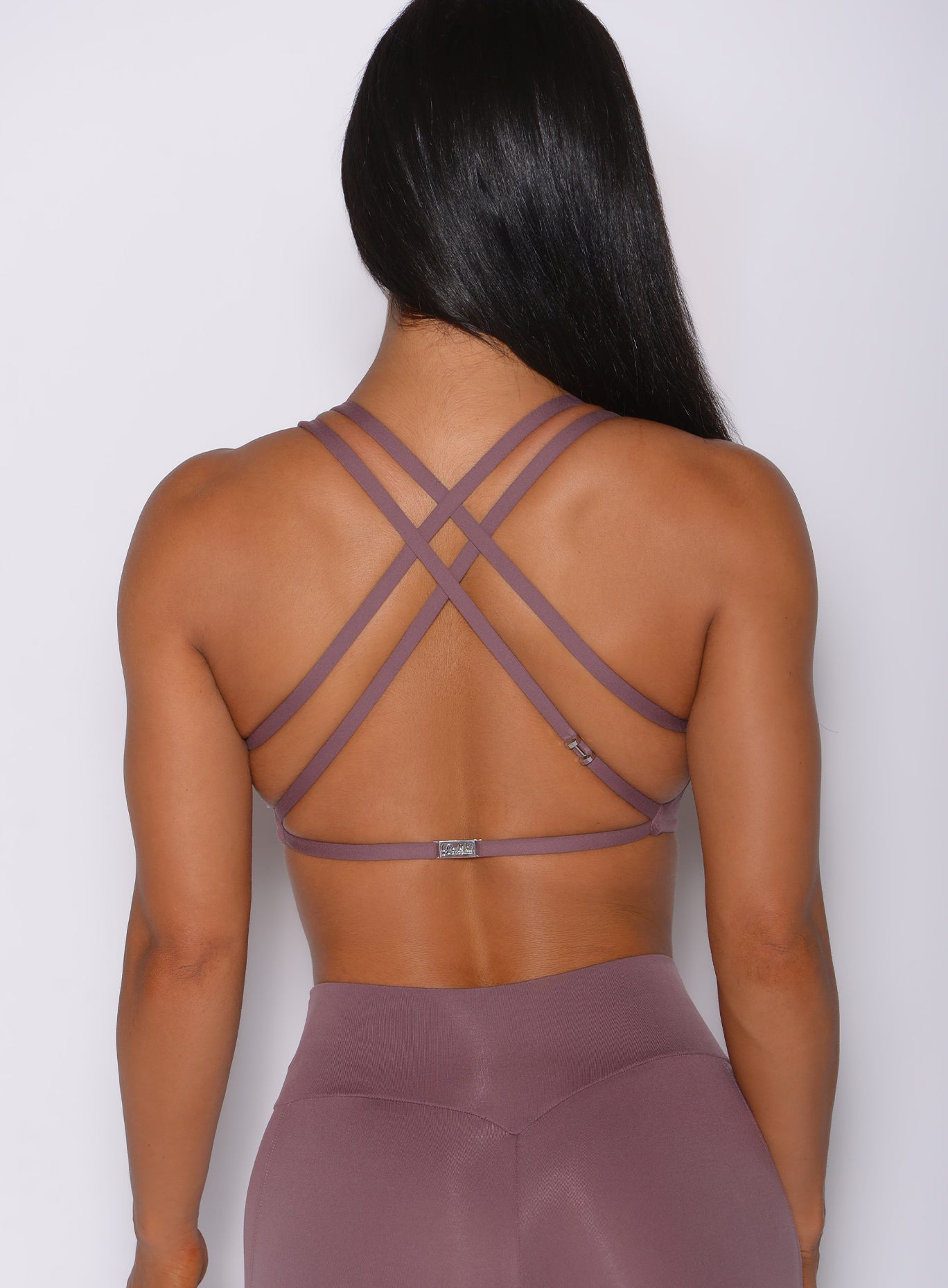 Zoomed in back profile view of a model in our mauve barbell sports bra and a matching leggings