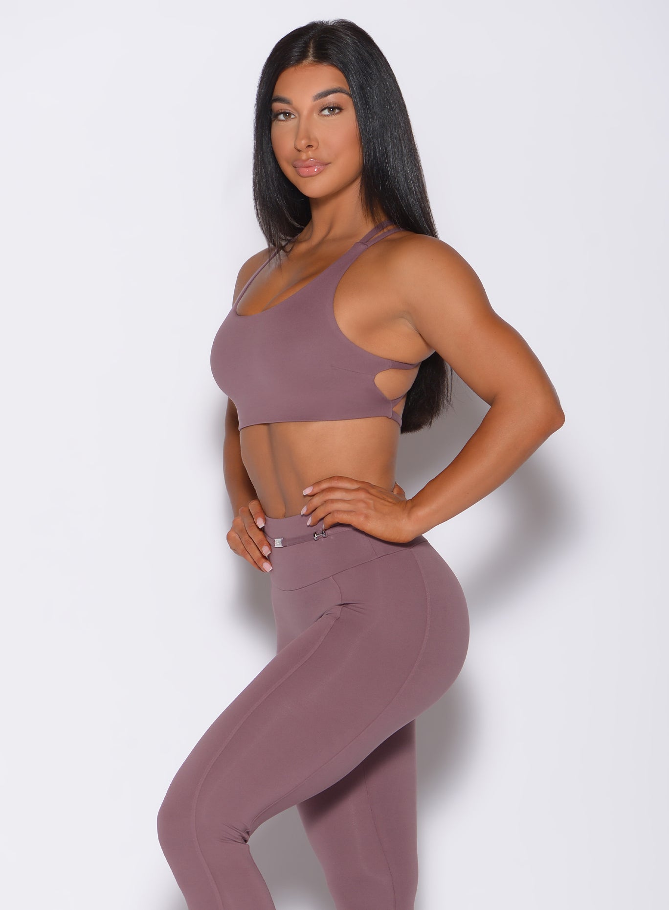 Left side profile view of a model with her hands on waist wearing our mauve barbell sports bra and a matching leggings