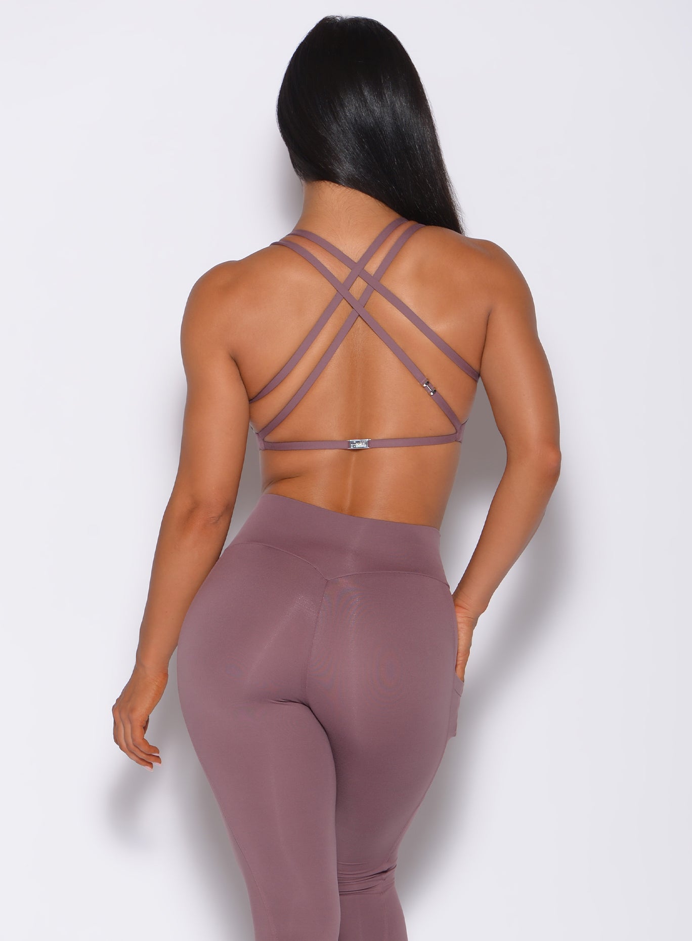 Back profile view of a model in our mauve barbell sports bra and a matching leggings 