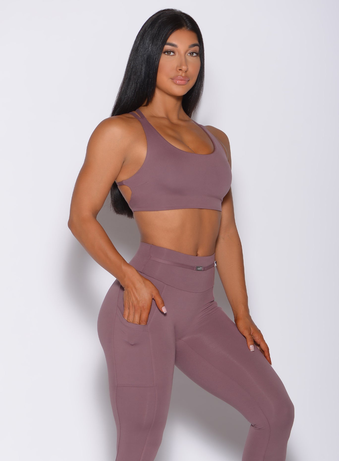 Right side profile view of a model with her right hand in pocket wearing our mauve barbell sports bra and a matching leggings