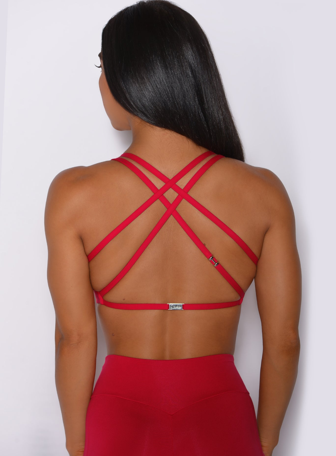 Zoomed in back profile view of a model in our red barbell sports bra and a matching leggings