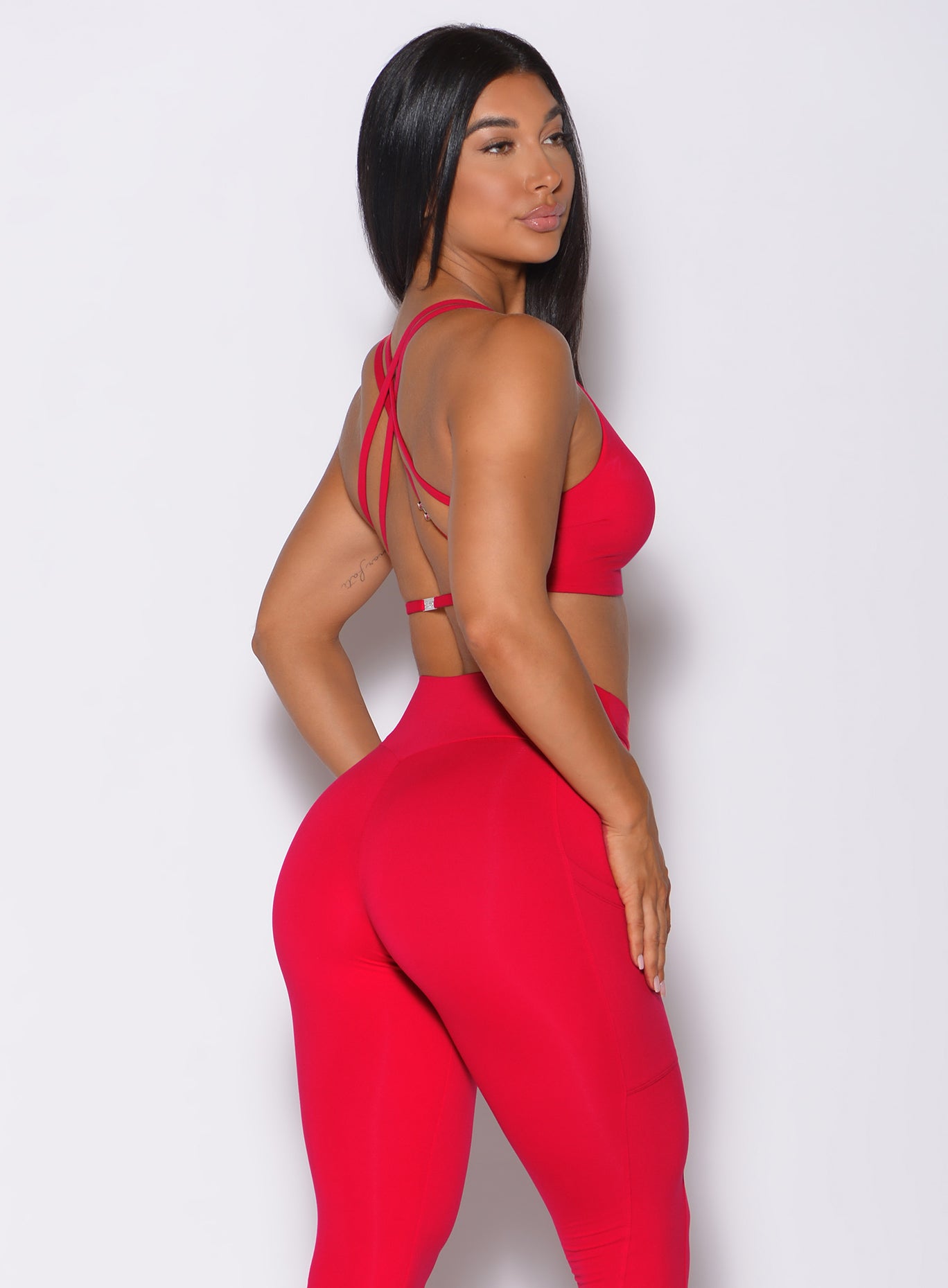 Right side profile view of a model wearing our red barbell sports bra and a matching leggings
