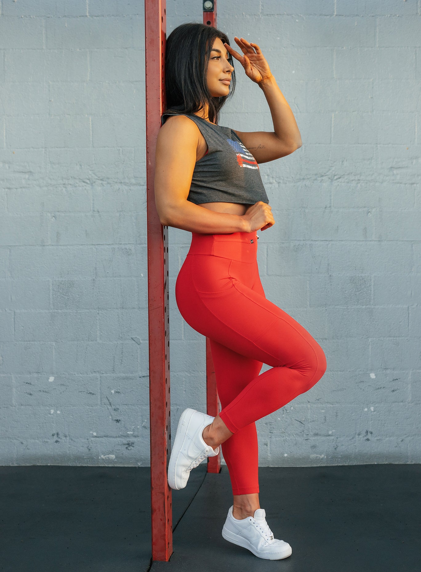 Right side profile view of a model in our red barbell leggings and a gray tee