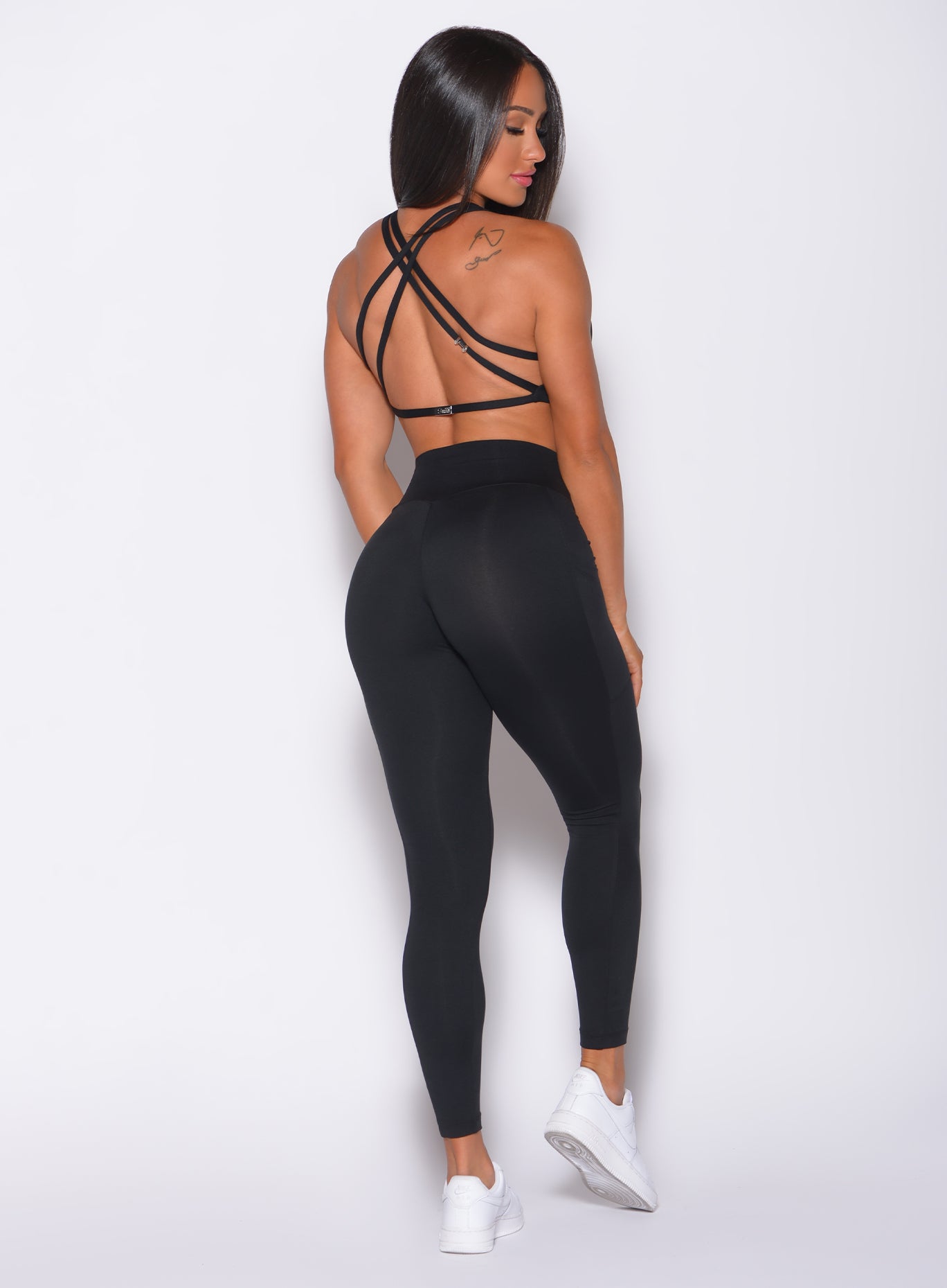 Back profile view of a model in our black barbell leggings and a matching bra 