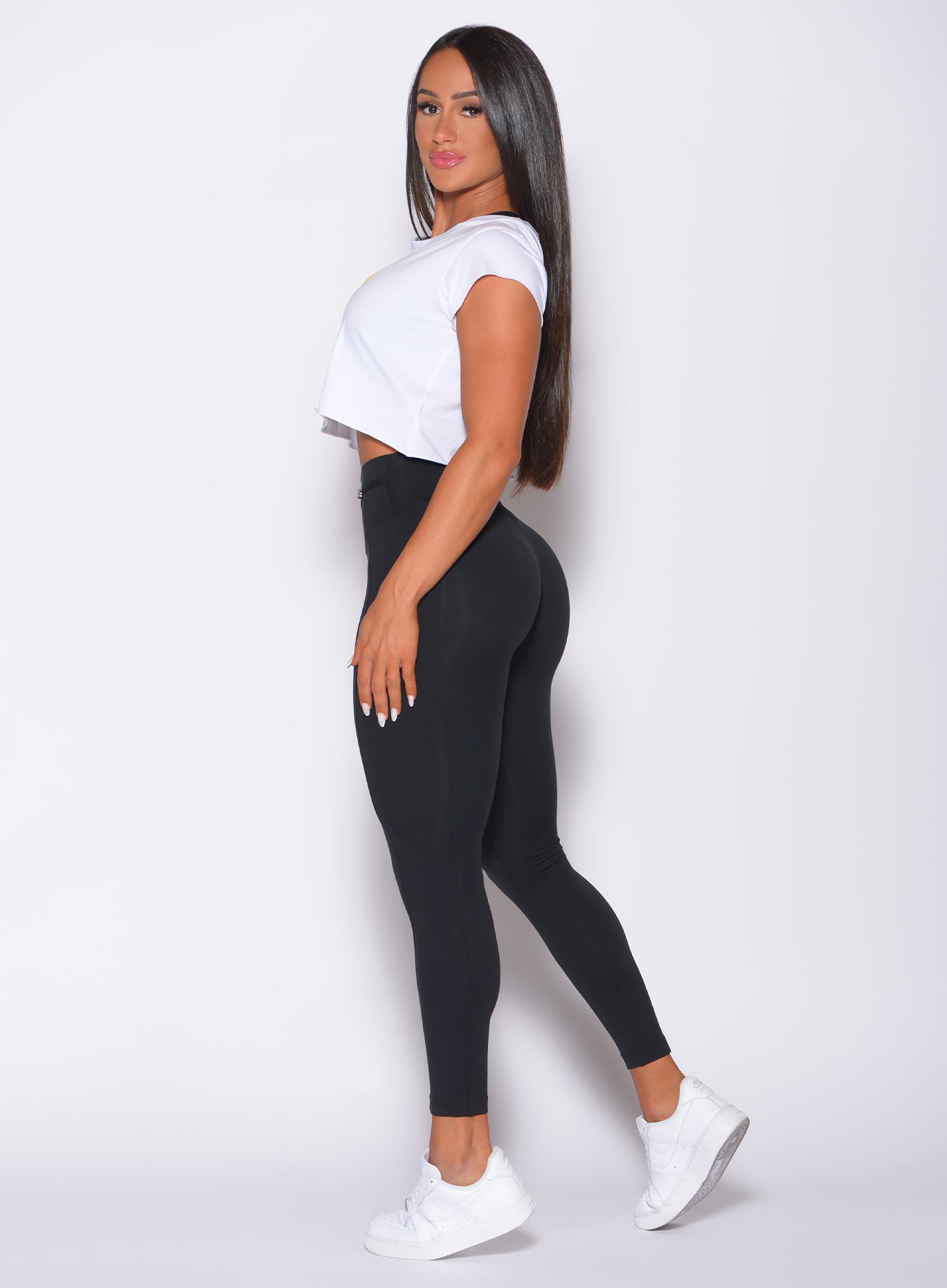 Left side profile view of a model facing to her left wearing our white mood tee and a black leggings