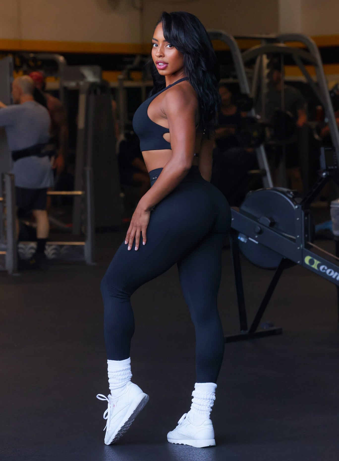 Left side  profile view of a model facing to her left wearing our black barbell leggings and a matching bra