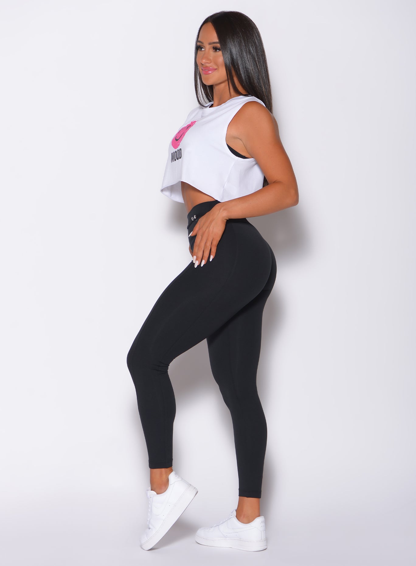 Left side profile view of a model in our white mood tank and a black high waist leggings