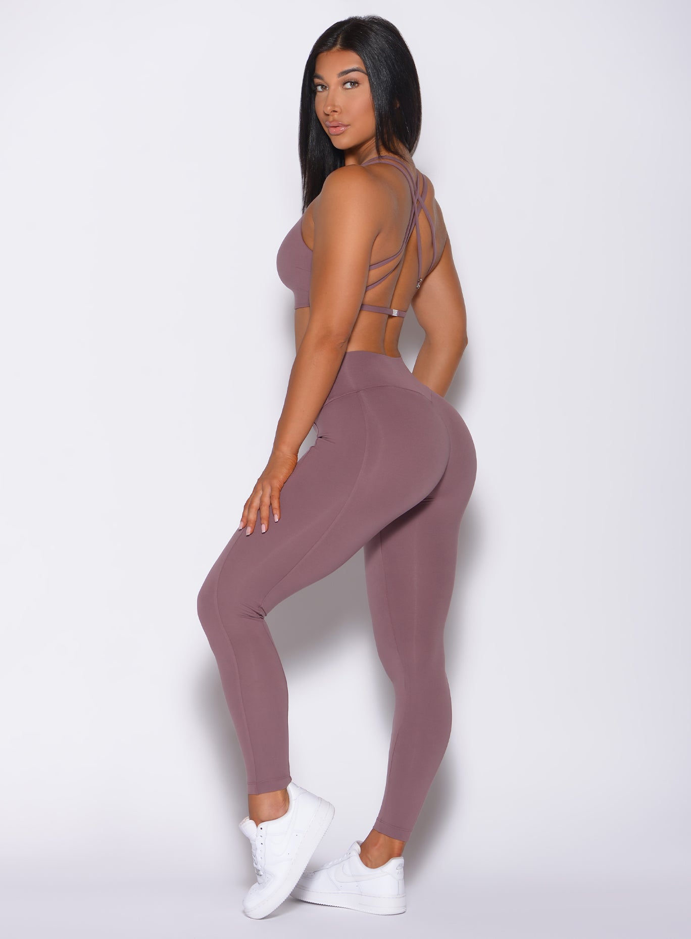 Left side profile view of a model facing to her left wearing our barbell legging in mauve color and a matching bra