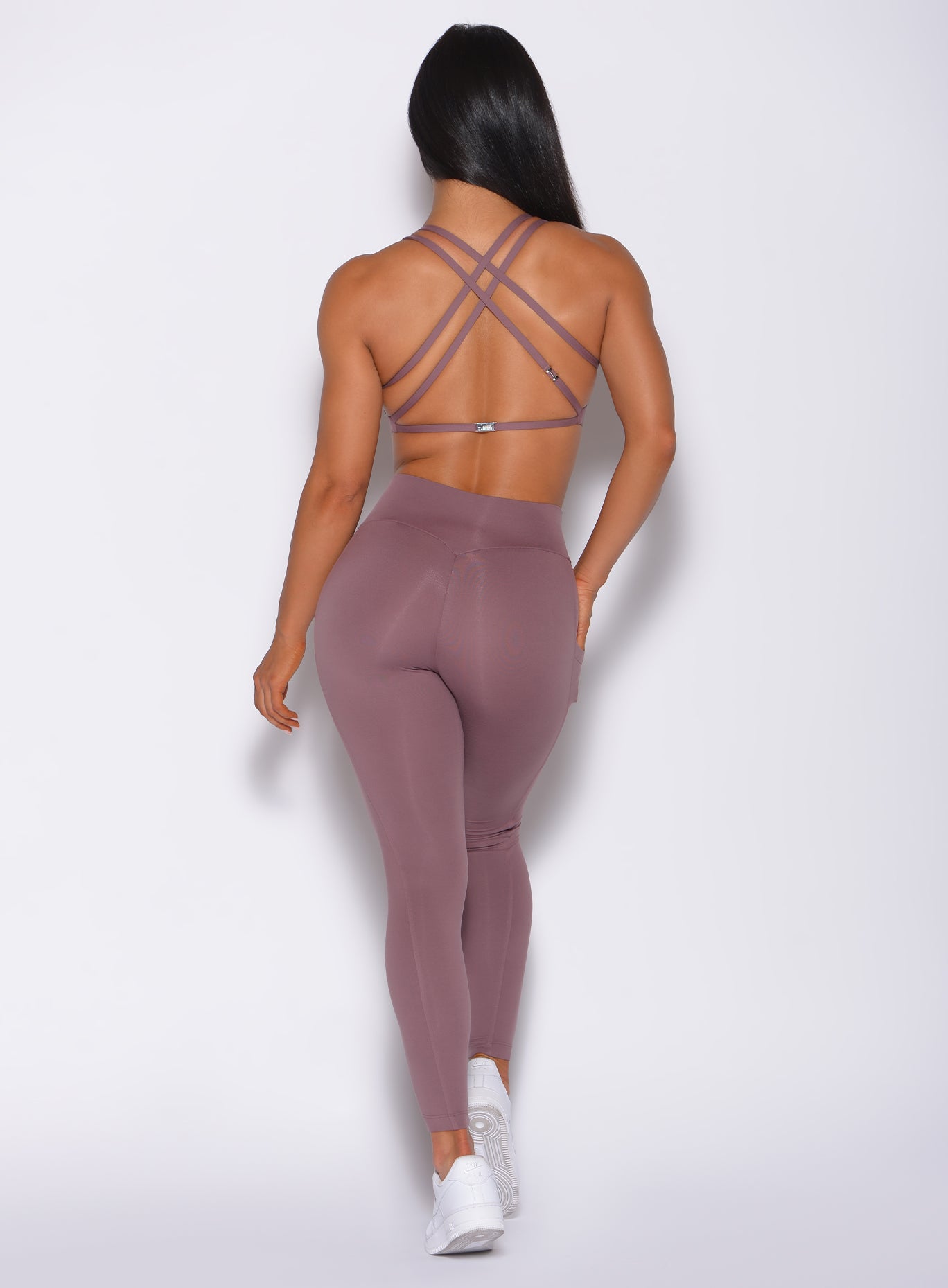 Back profile view of a model in our barbell legging in mauve color and a matching bra