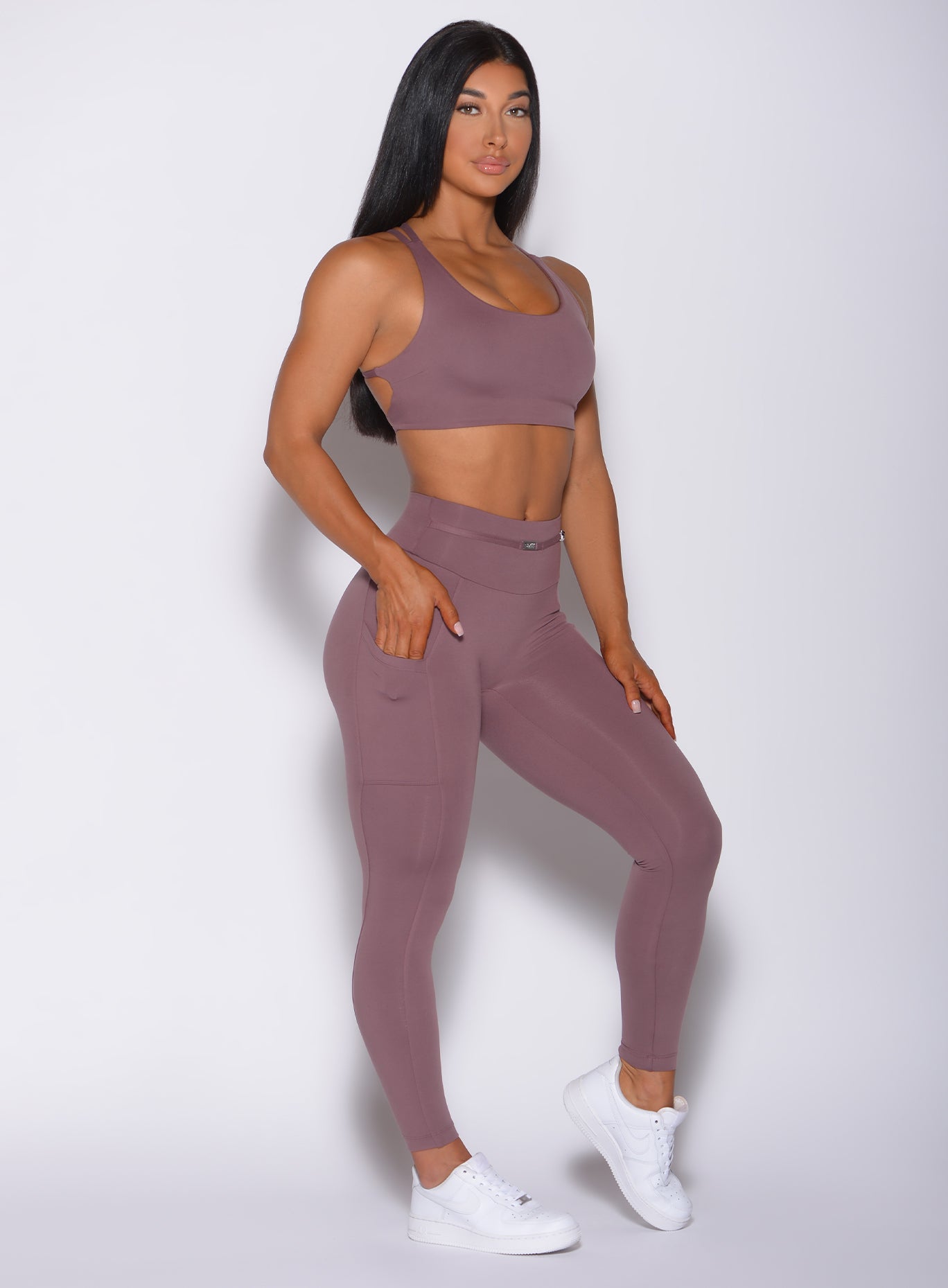 Right side profile view of a model angled right wearing our barbell legging in mauve color and a matching bra