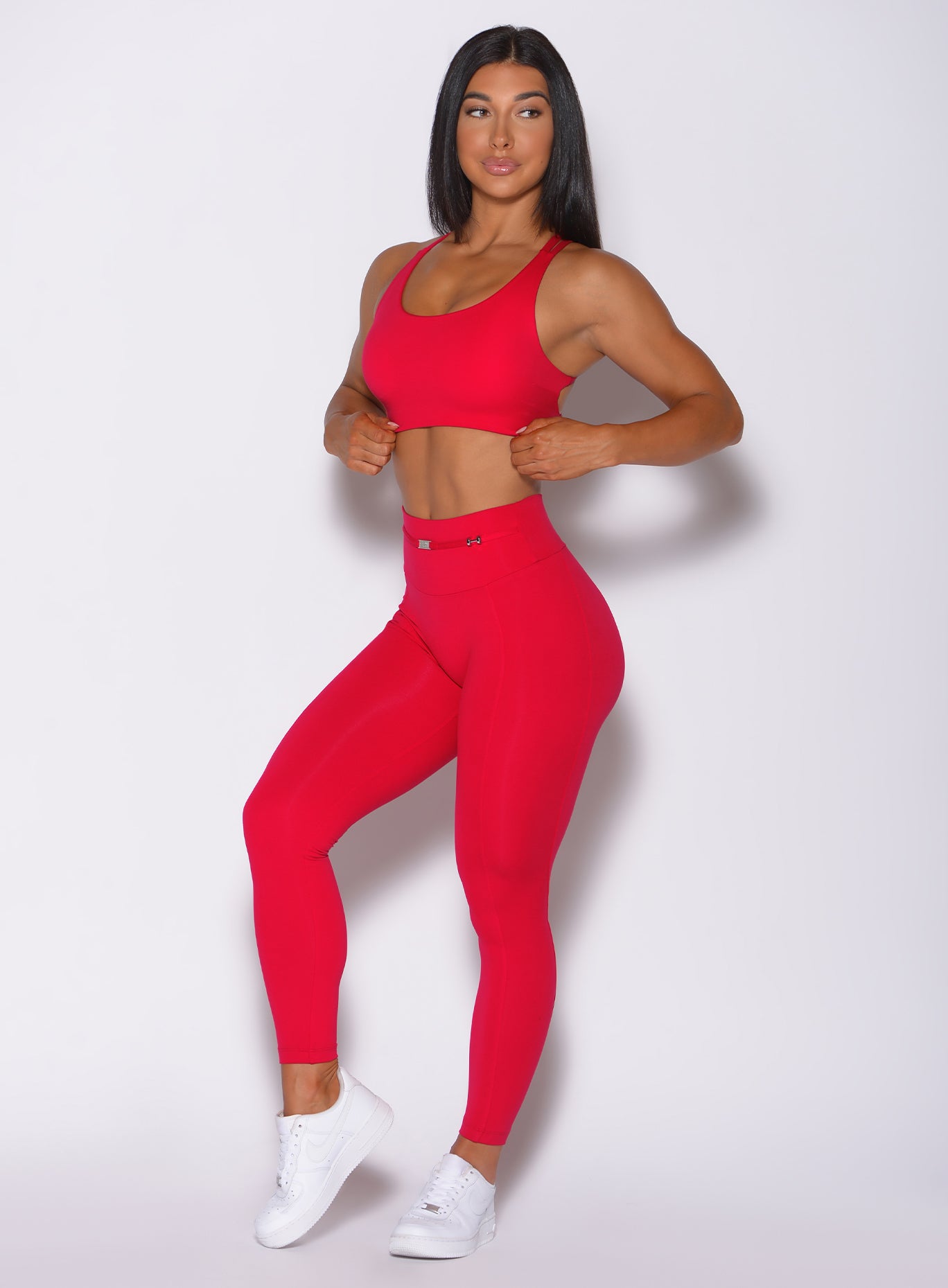 Left side profile view of a model angled left wearing our red barbell sports bra and a matching leggings