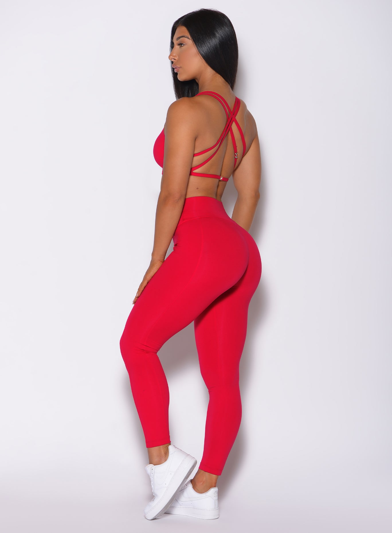 Left side profile view of a model in our red barbell leggings and a matching bra 