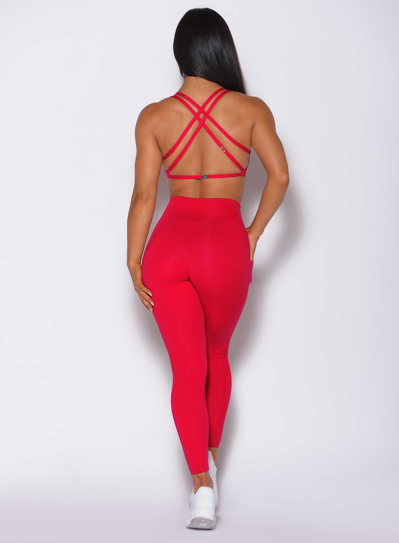 Back profile view of a model in our red barbell leggings and a matching bra 