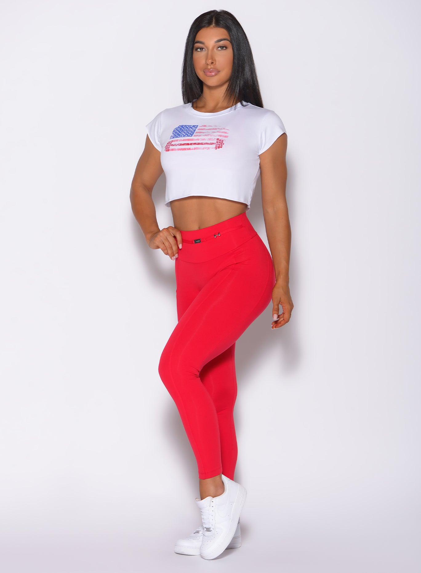 Left side profile view of a model angled left wearing our white USA Barbell tee and a red leggings