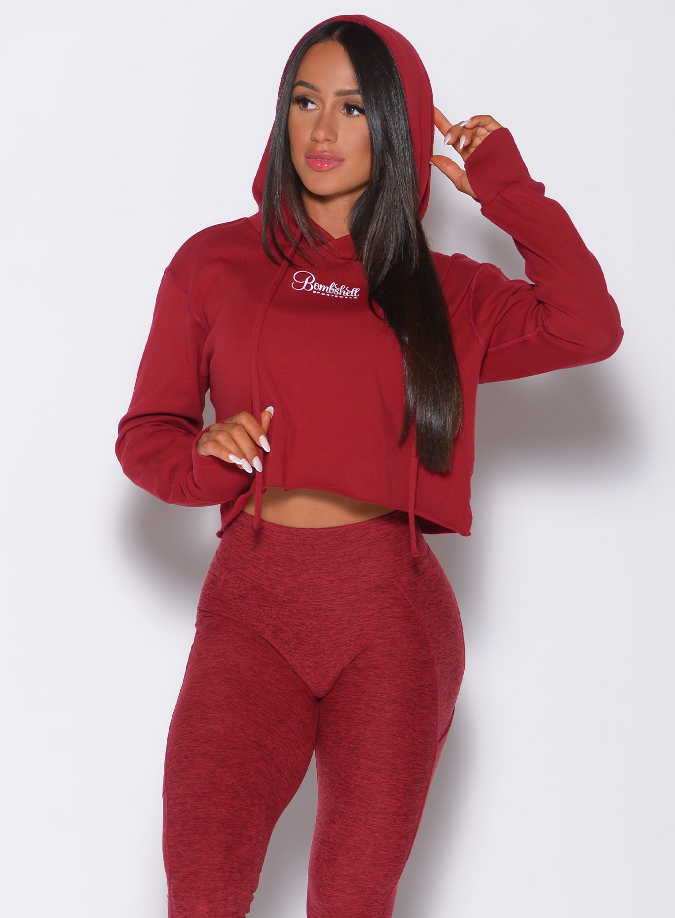 Front profile view of a model wearing our bombshell hoodie in red rose color and a matching leggings