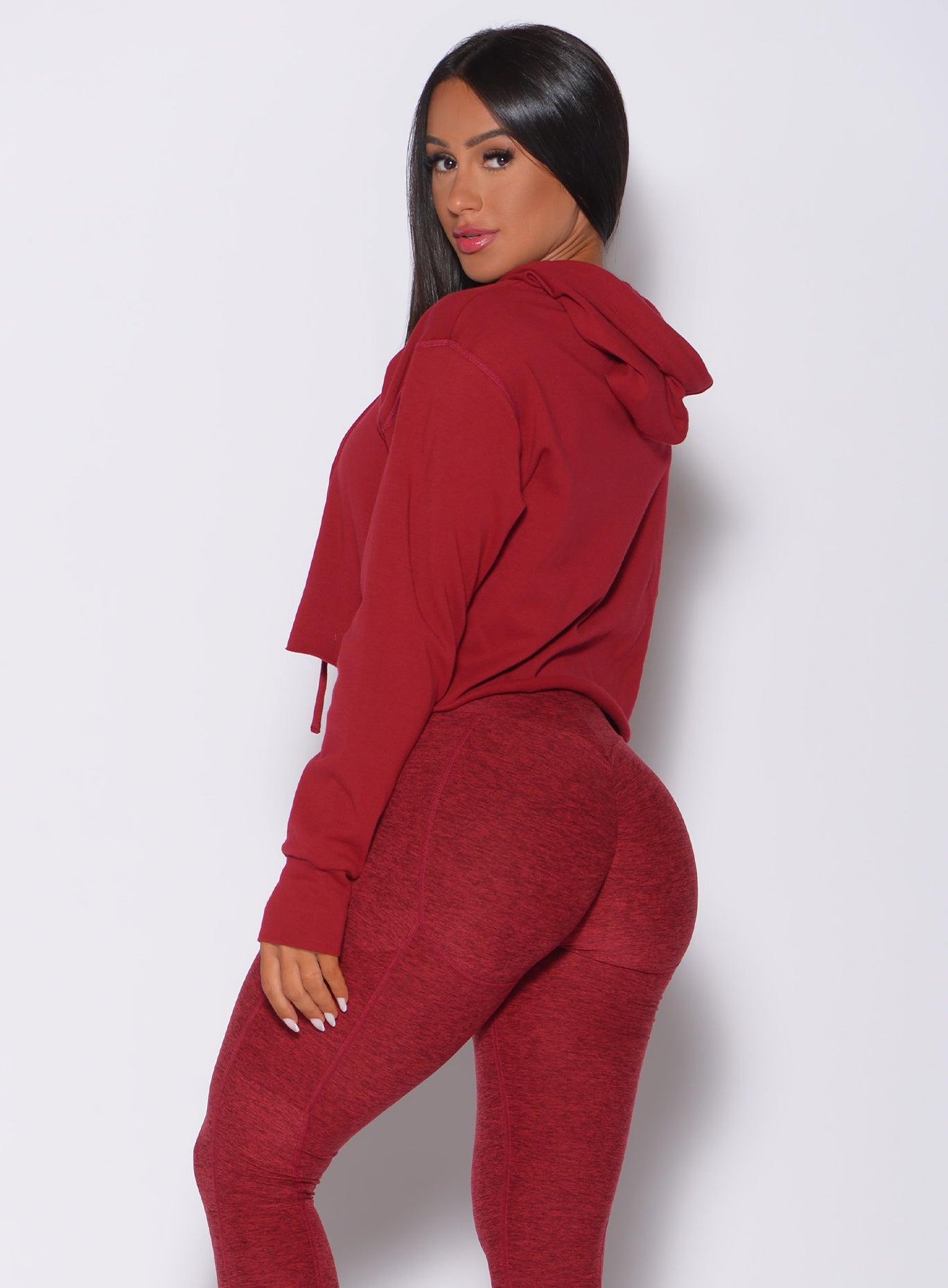 Left side profile view of a model in our bombshell hoodie in red rose color and a matching leggings