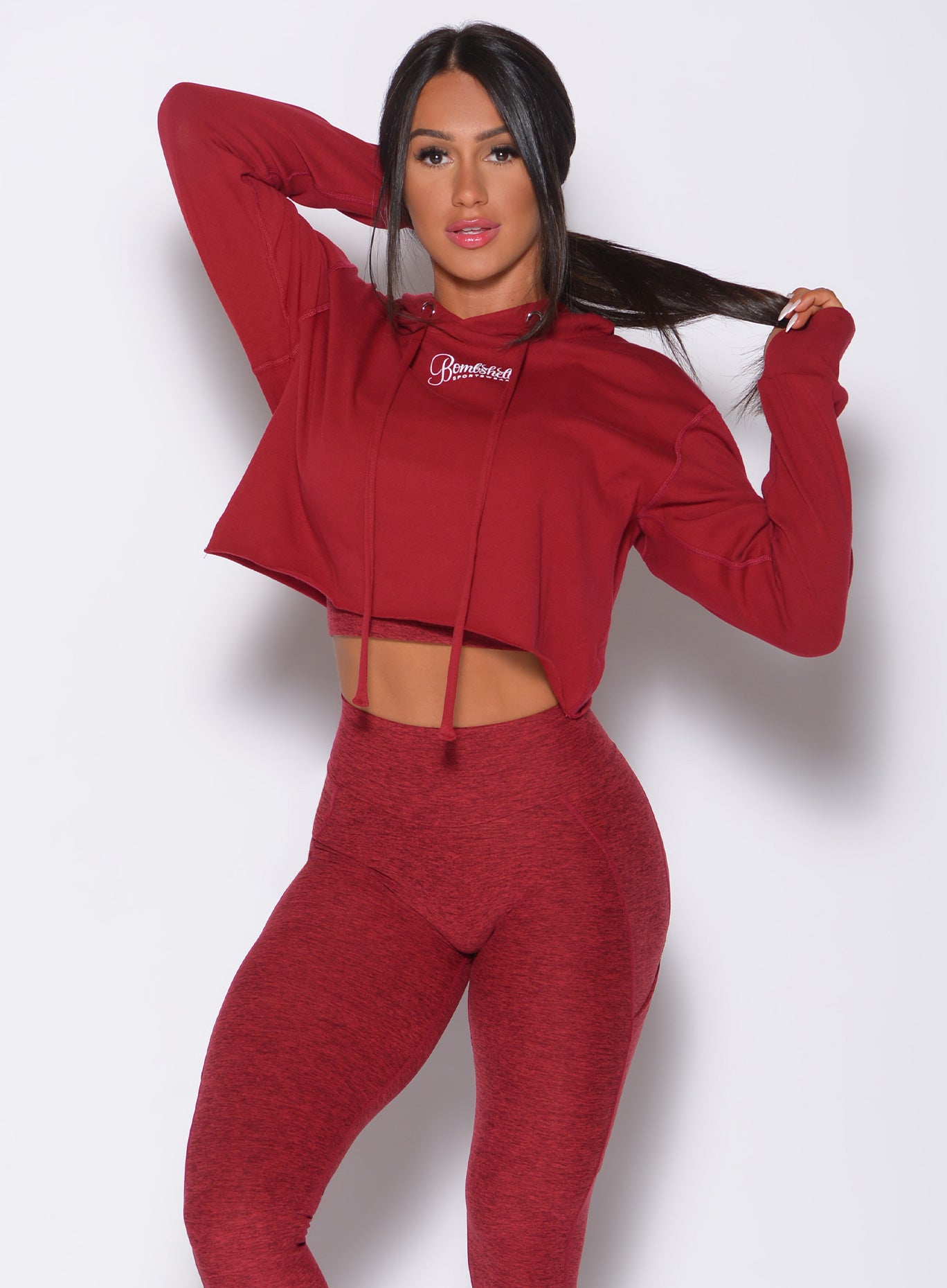 Front profile view of a model in our bombshell hoodie in red rose color and a matching leggings