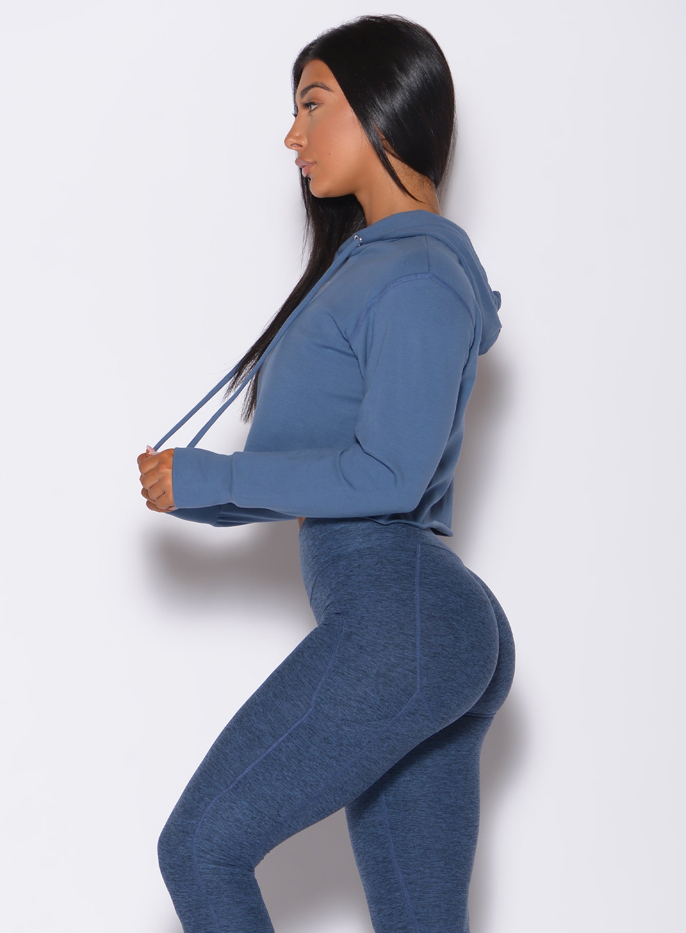 Left side  profile view of a model wearing our bombshell hoodie in blue star color and a matching leggings