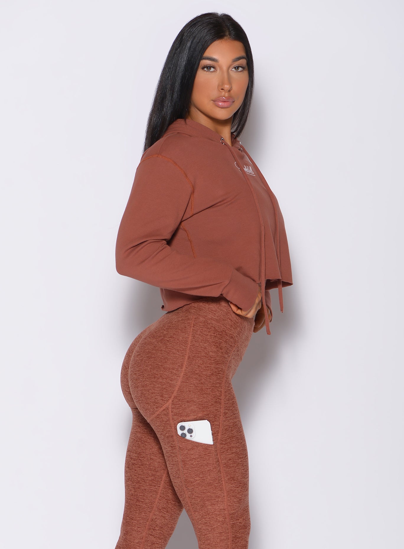 Right side profile view of a model in our bombshell hoodie in caramel color and a matching leggings