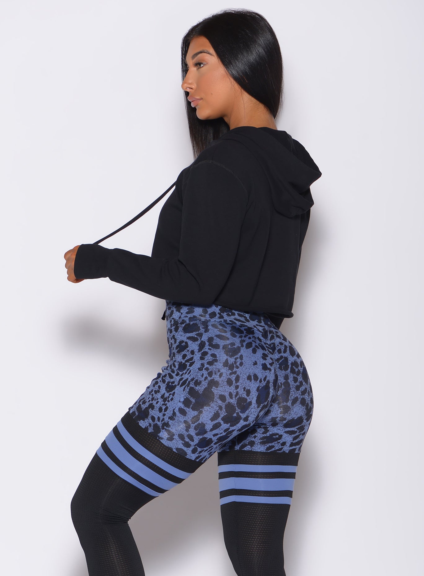 Left side  profile view of a model in our black bombshell hoodie and a cheetah print leggings