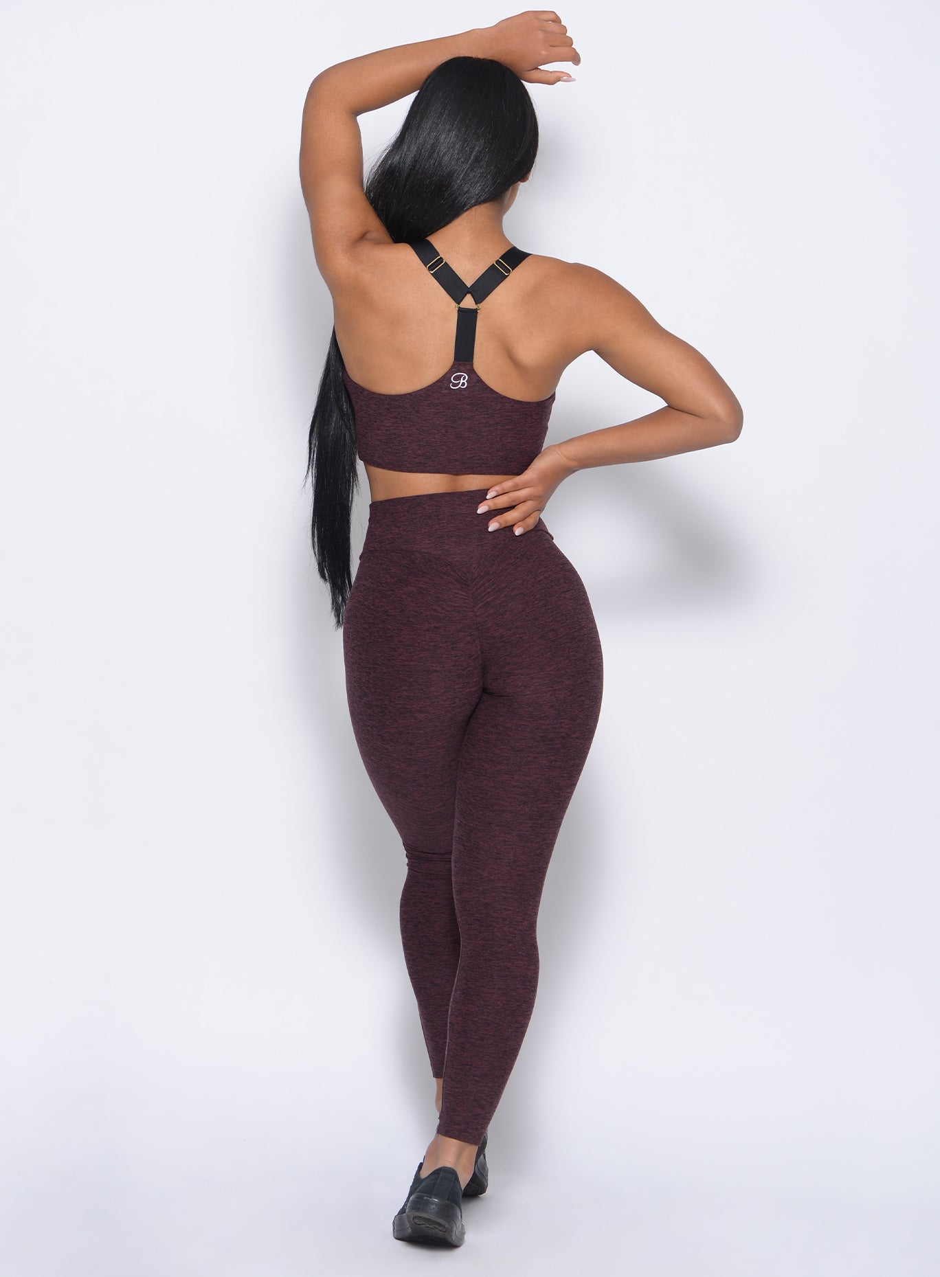 Back view of the model wearing our boost leggings in port color and a matching bra