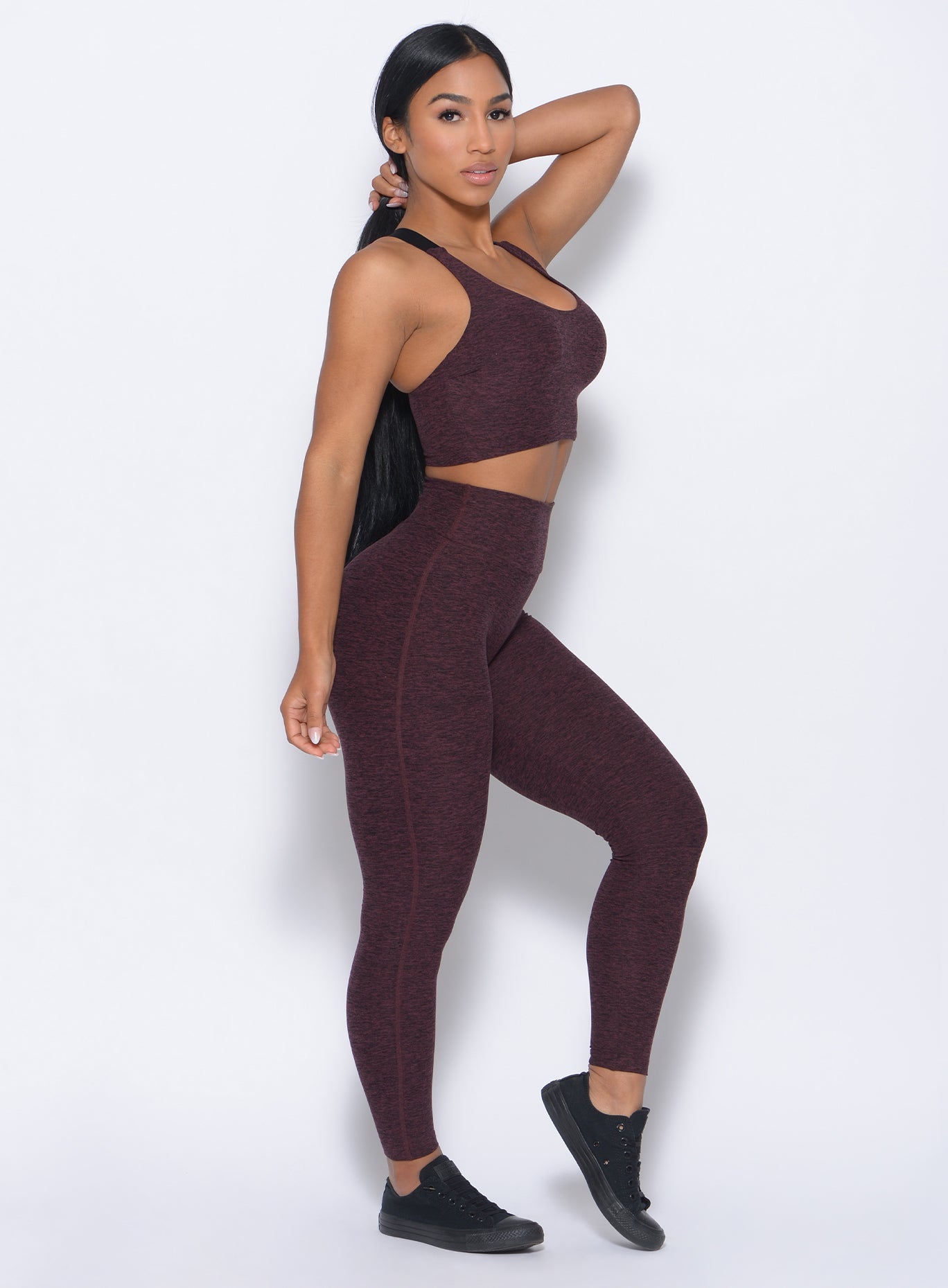 Right side view of the model wearing our boost leggings in port color and a matching bra
