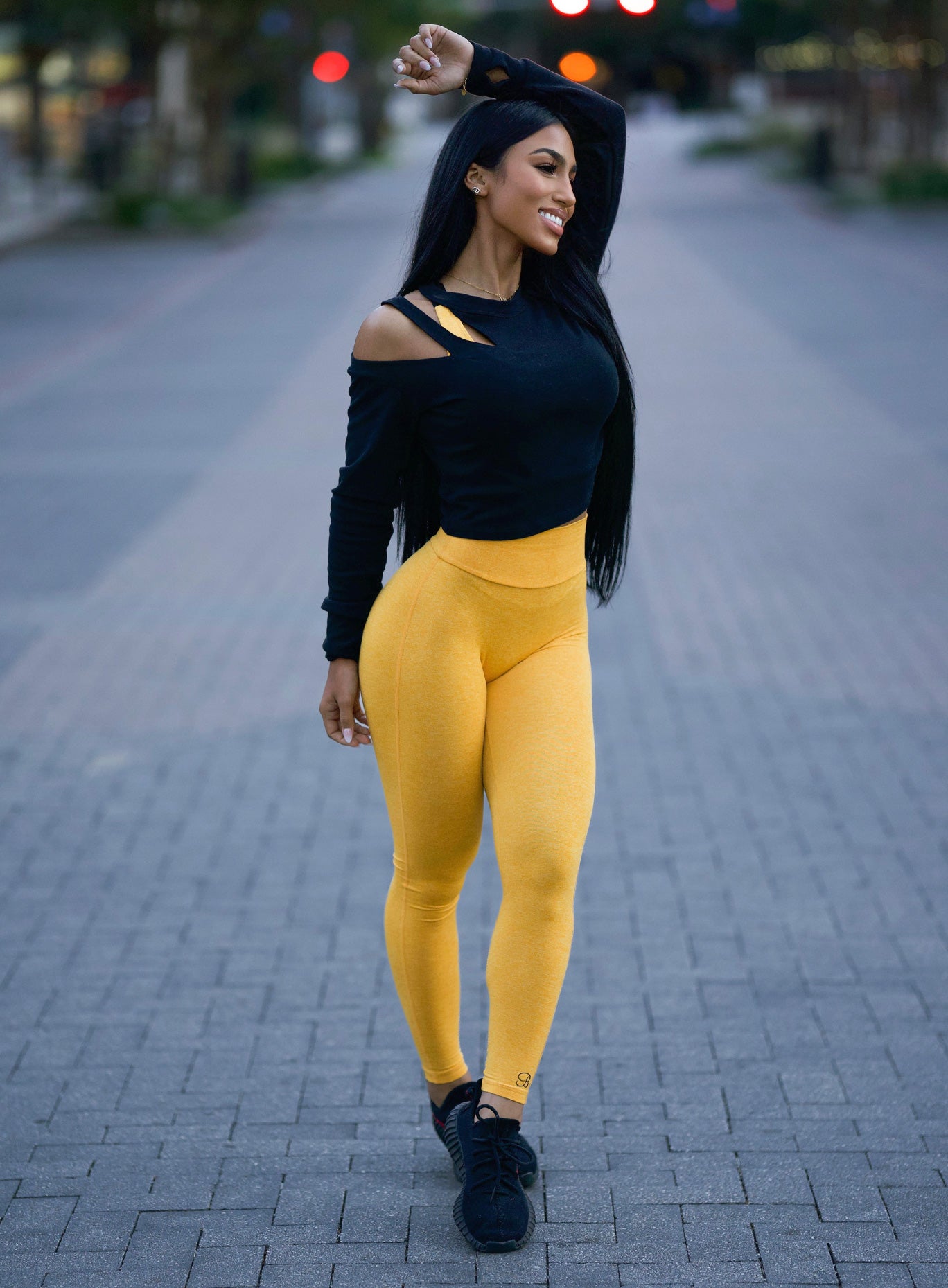 Right side view of the model wearing our boost leggings in sunkissed color and a black top