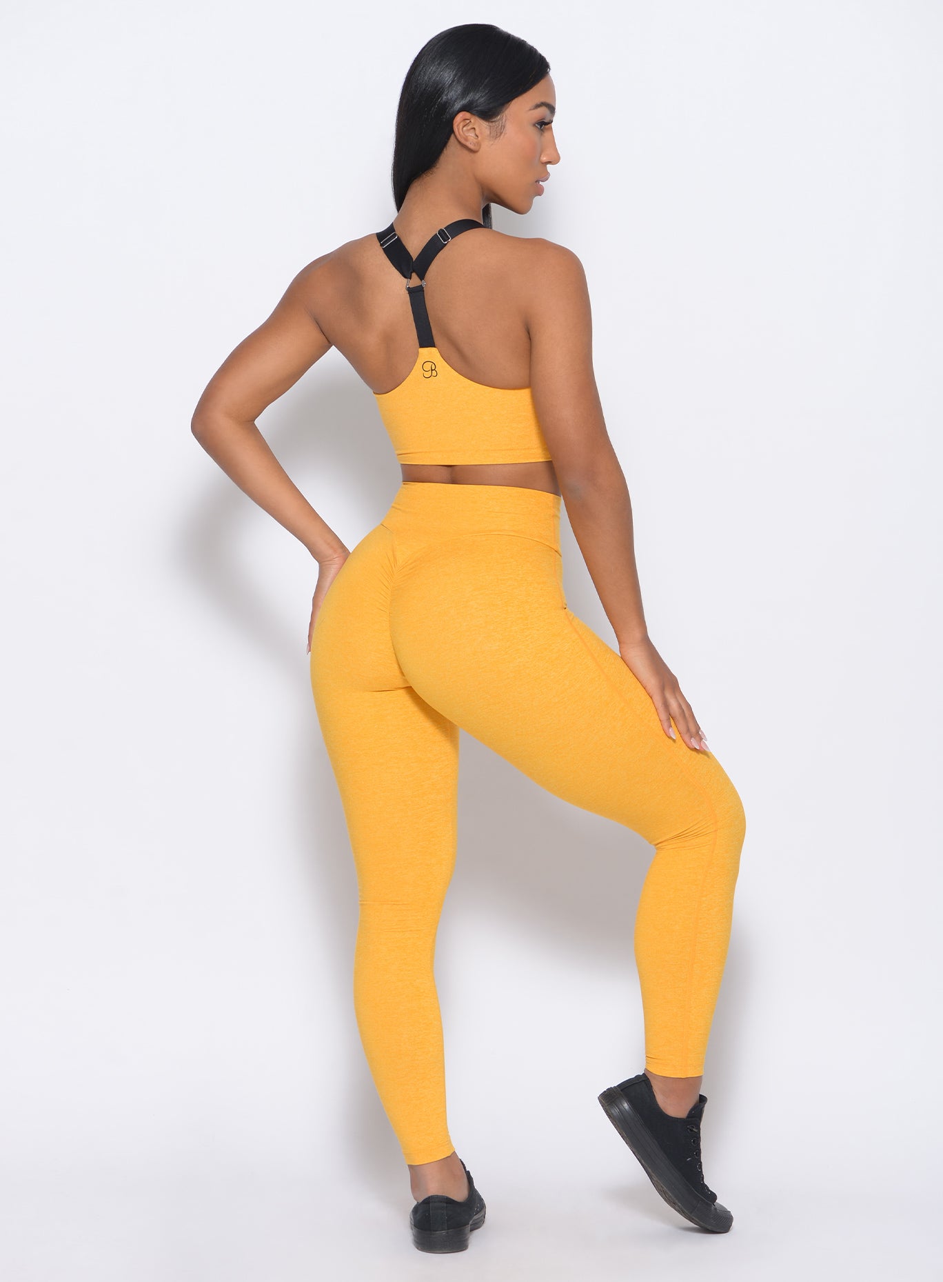 Back view of the model in our boost leggings in sunkissed color and a matching bra