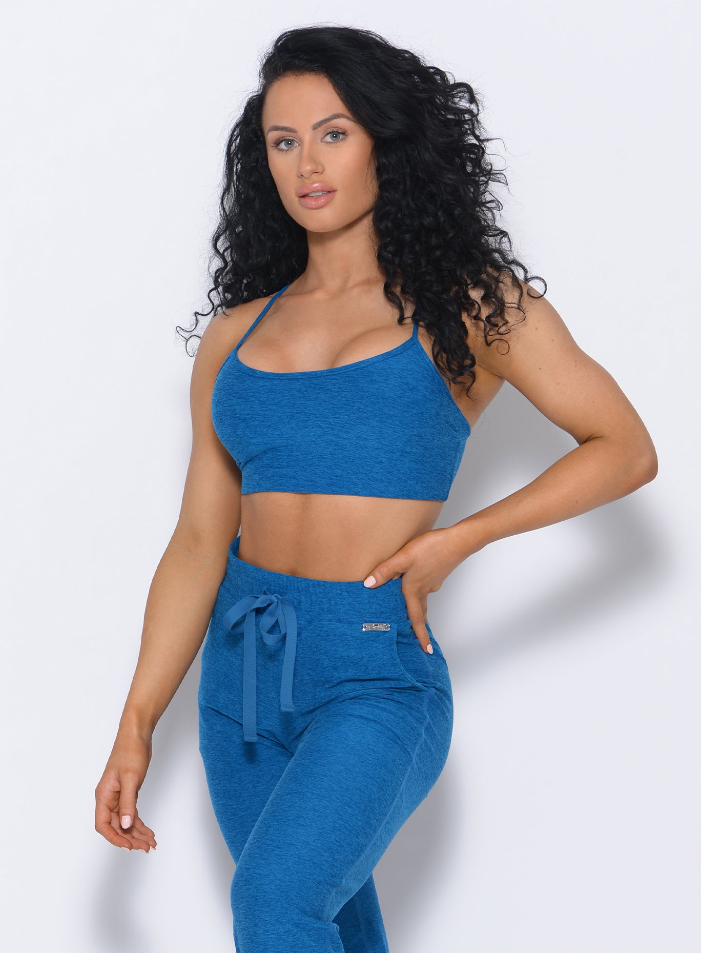 Front profile view of the model in our Relax Sports Bra in azure color and a matching joggers 