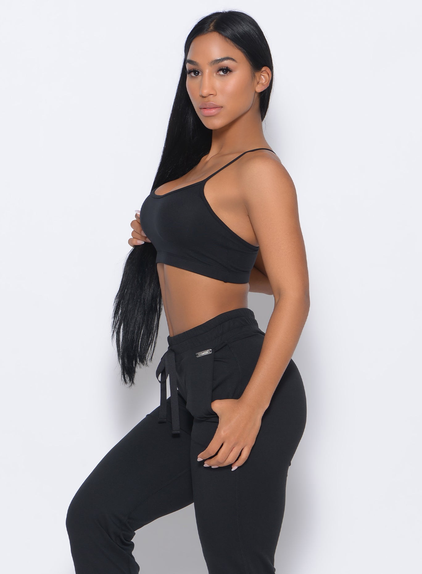 Left side view of the model holding her hair in our black Relax Sports Bra and a matching joggers