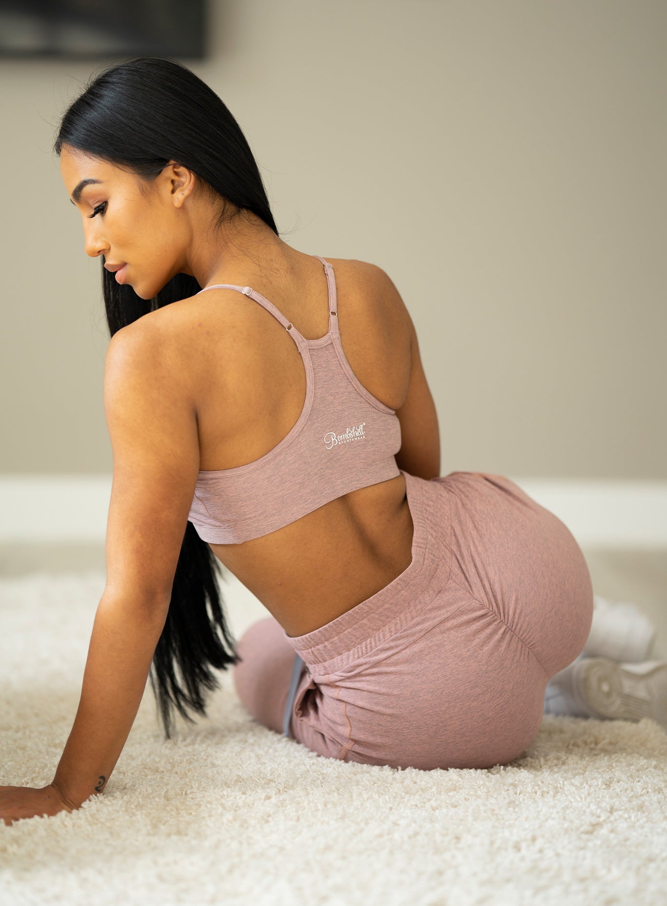 Back view of the model sitting down wearing our relax sports bra in sand dune color and a matching joggers