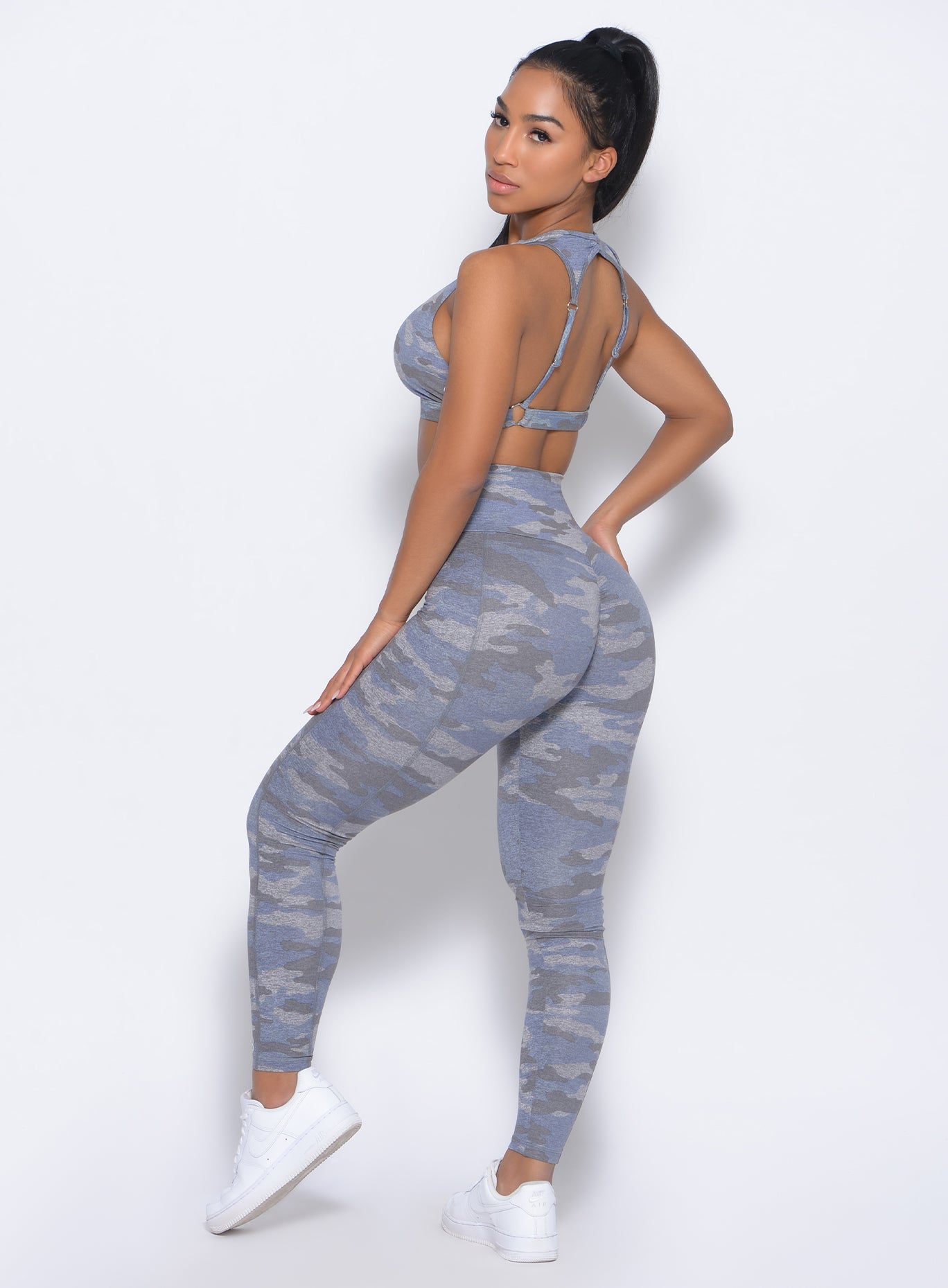 Left side view of the model facing to her left in our Brazilian contour leggings in silver camo color and a matching bra