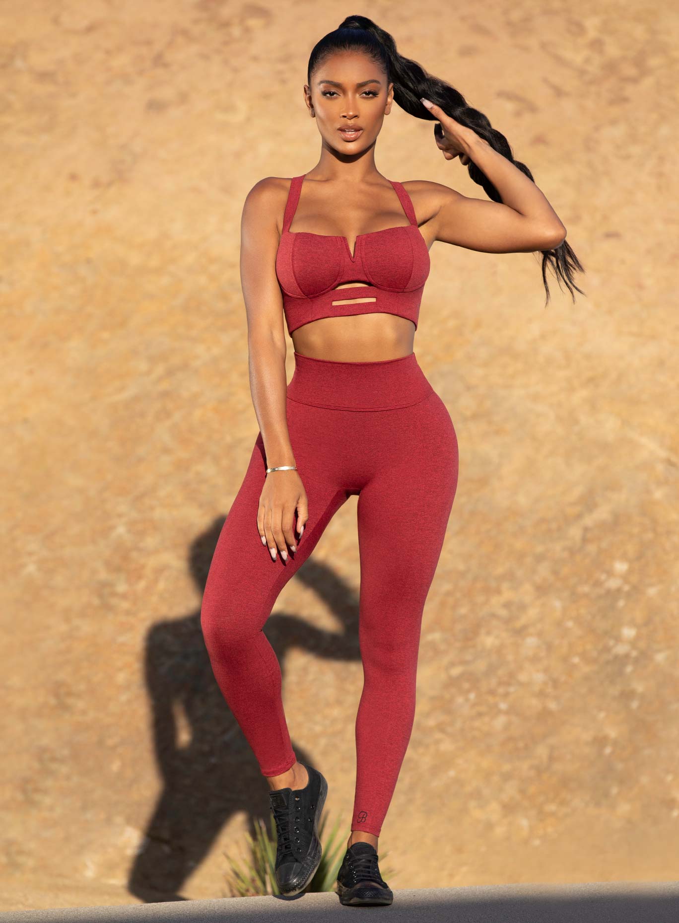 Front view of the model in a red high waist leggings with a V back design