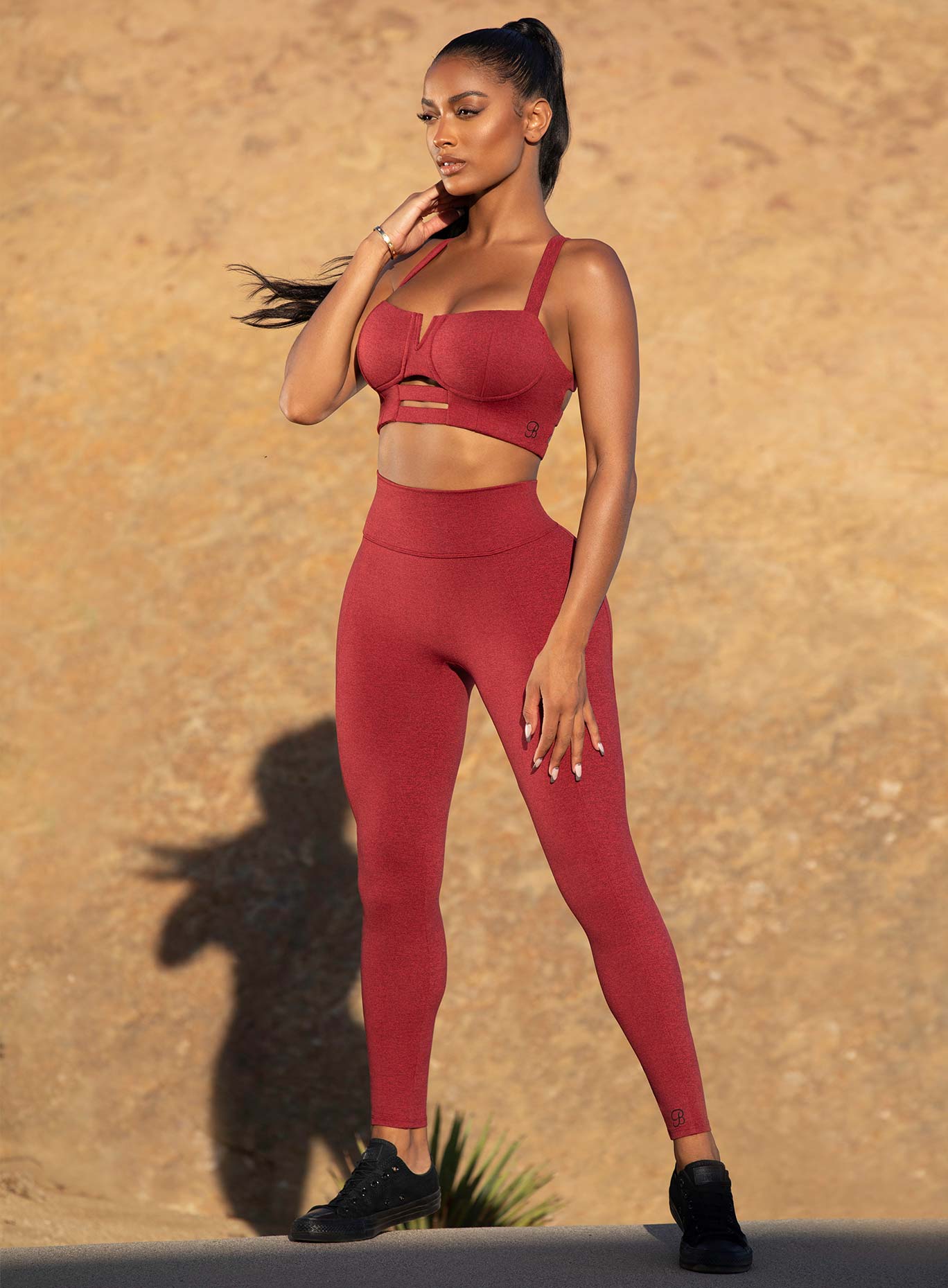 Three quarters view of the model in a red high waist leggings with a V back design