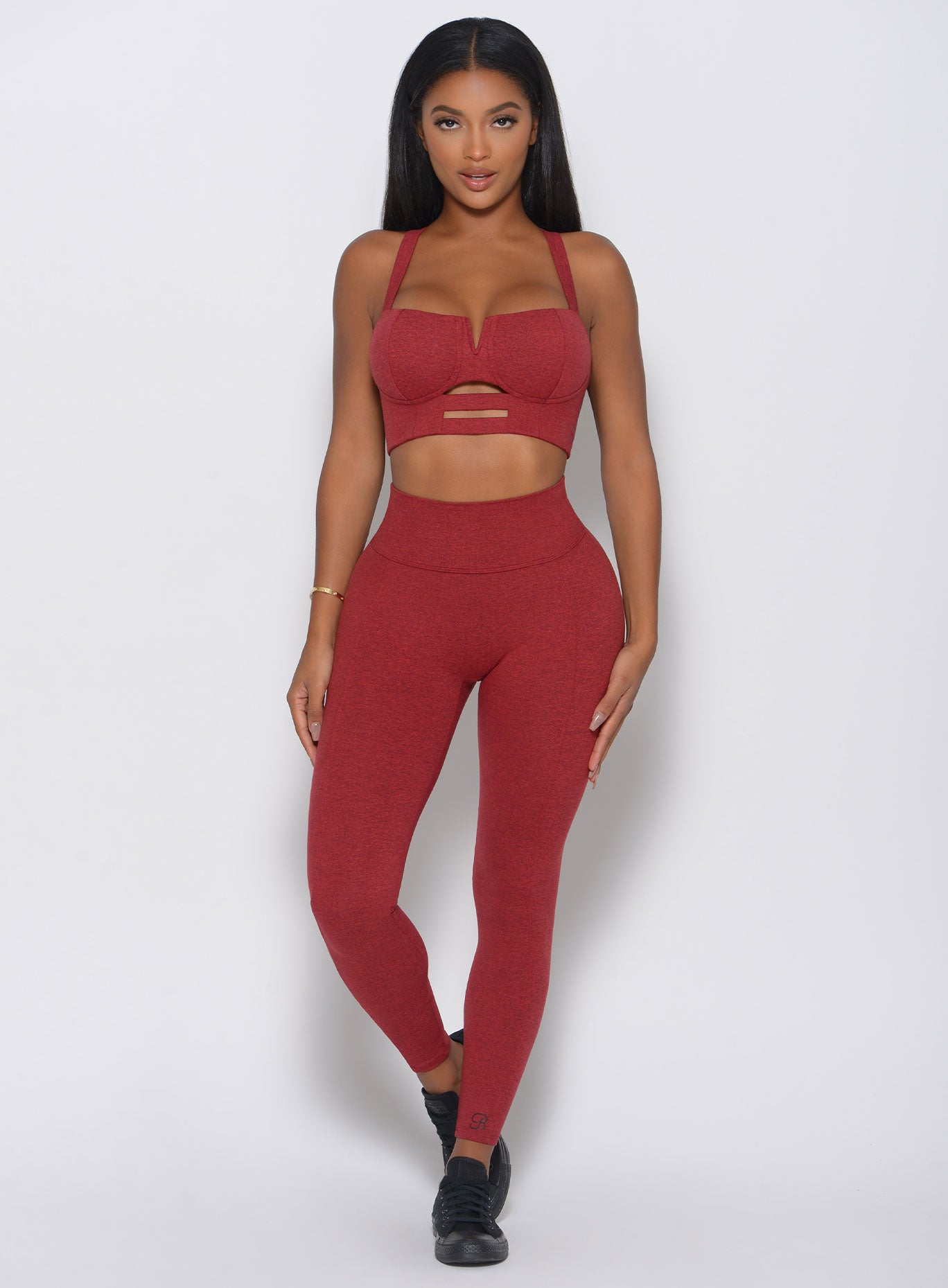 Model facing forward in a red high waist leggings with a V back design
