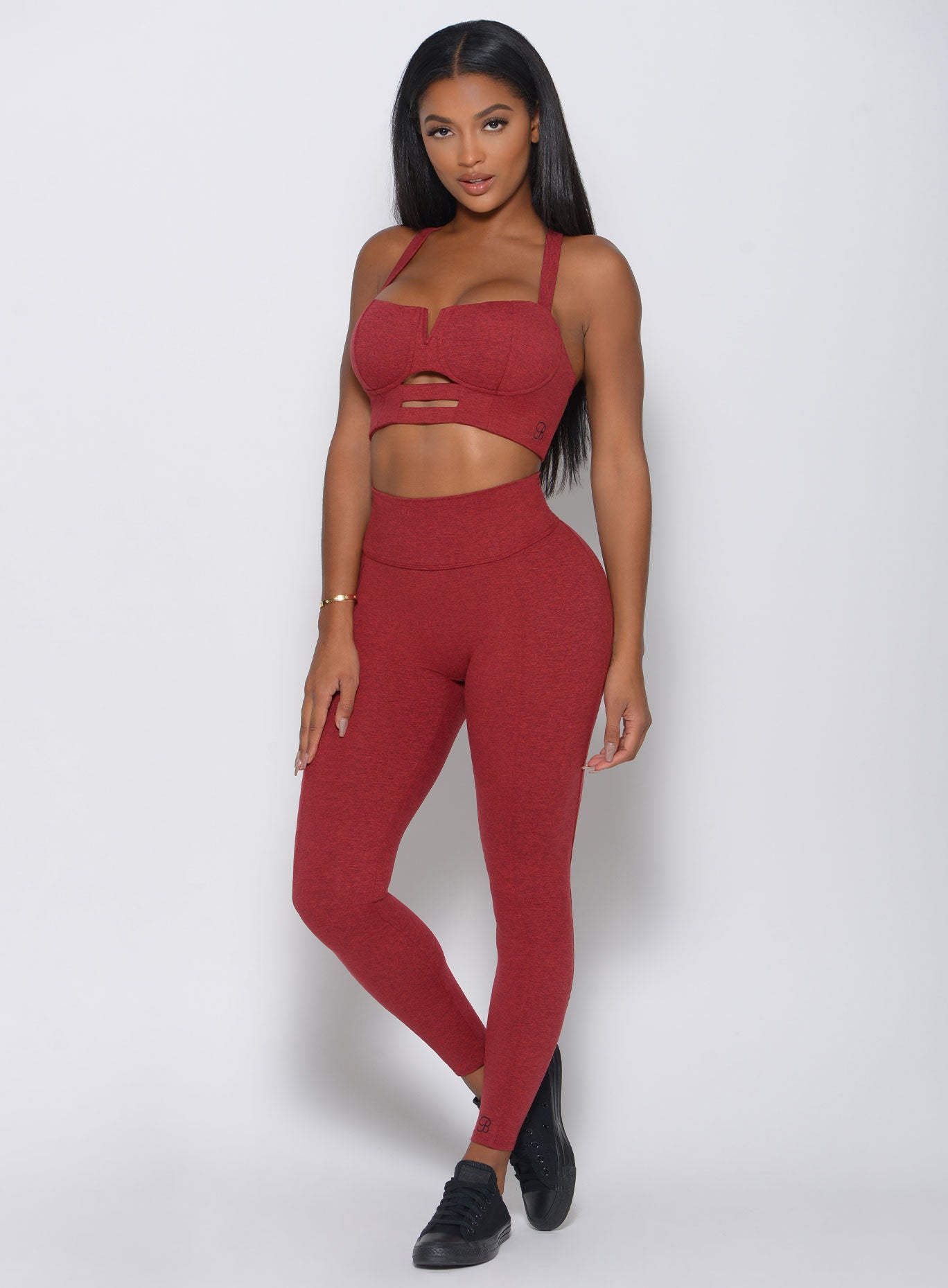 Front view of the model in a red high waist leggings with a V back design and a matching bra 