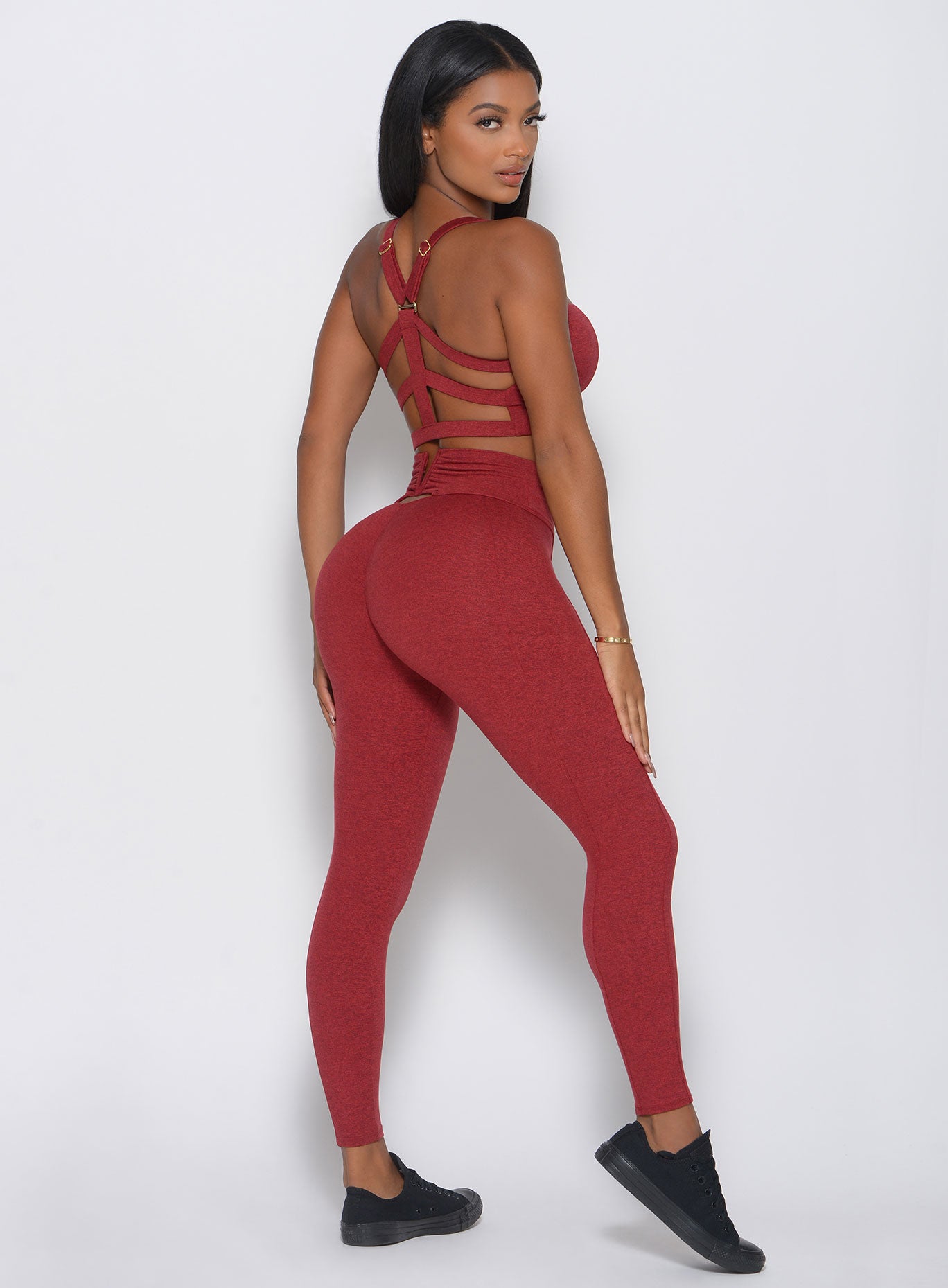 Back iew of the model in a red high waist leggings with a V back design