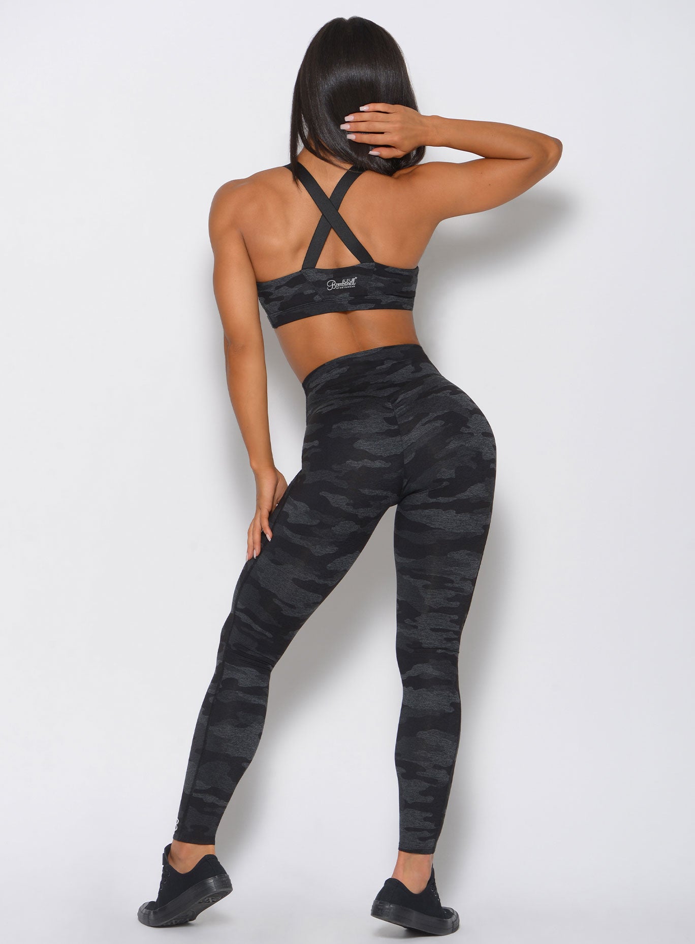 Back view of the model in a camo leggings in charcoal color and a matching bra 