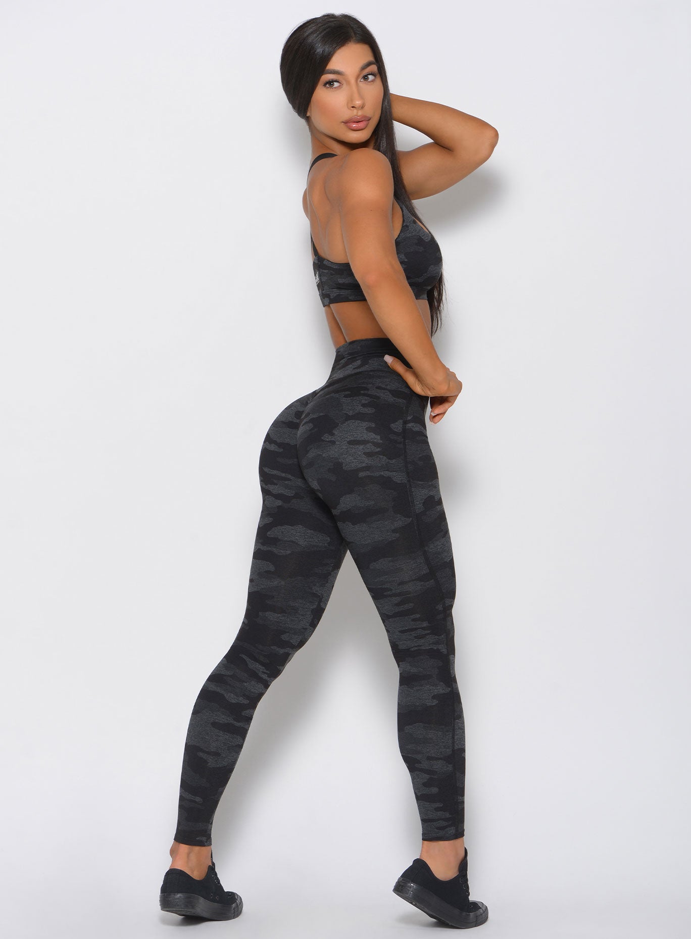 Right side profile of the model in the Fit Camo Leggings in charcoal color.  