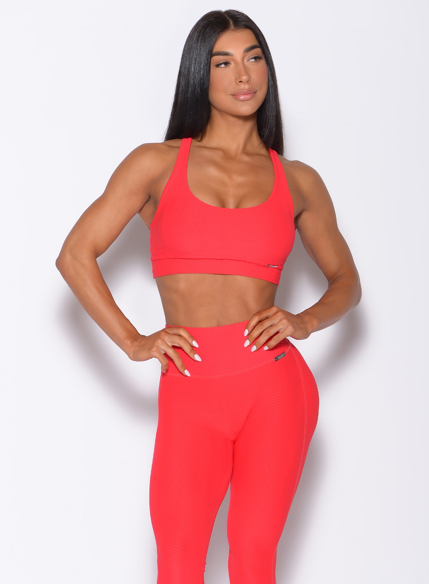 Front profile view of a model in our chevron sports bra in flame red color and a matching leggings