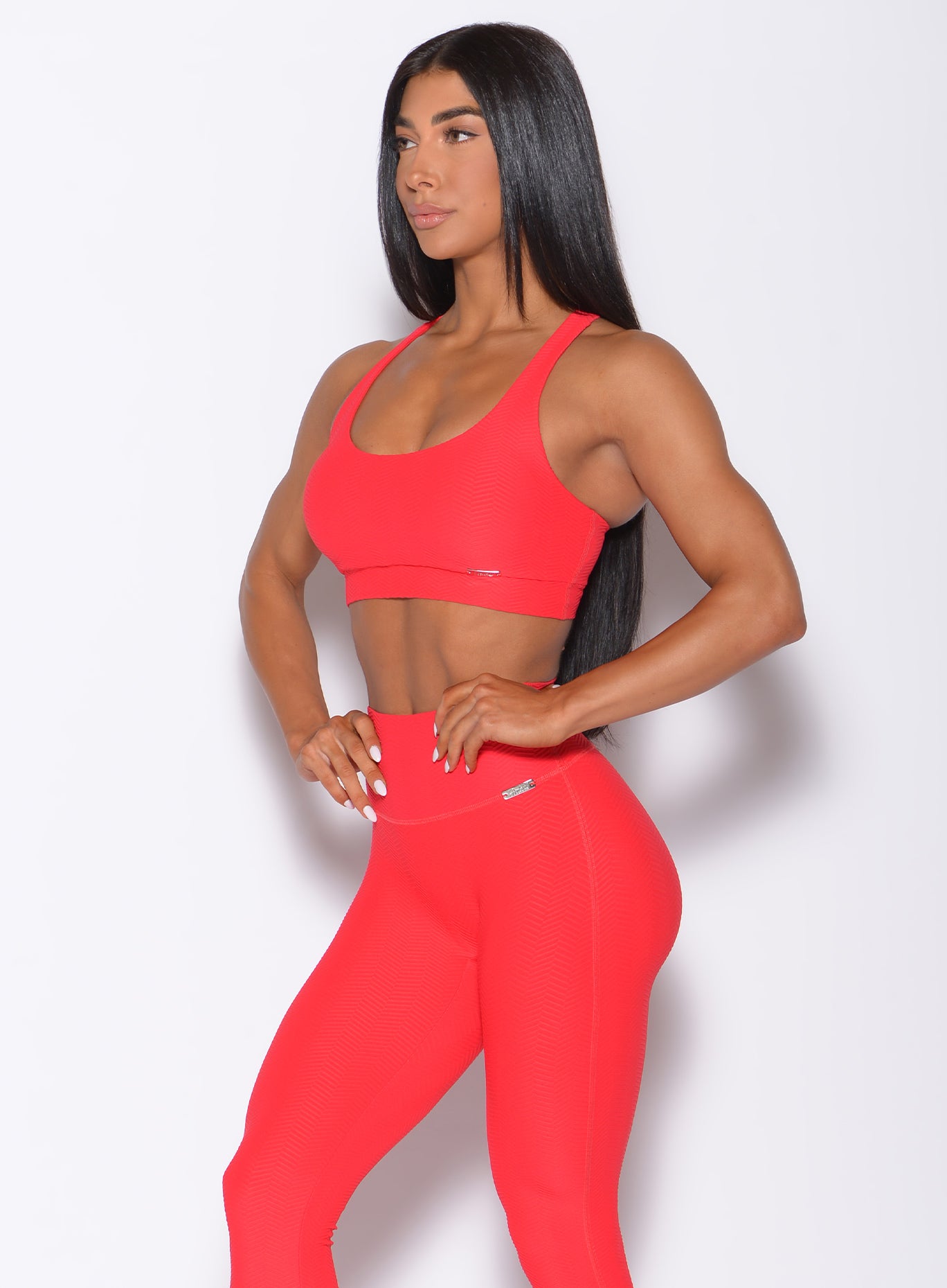 Left side profile view of a model angled left wearing our chevron sports bra in flame red color and a matching leggings