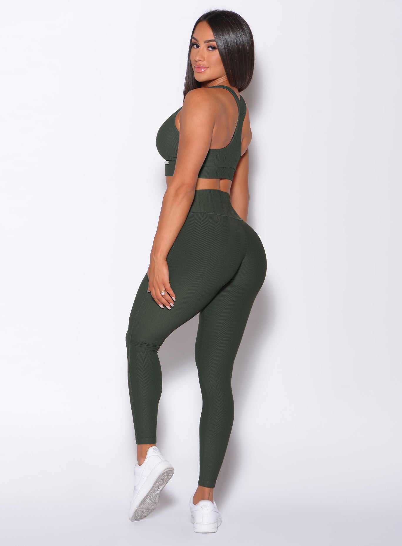 Left side profile view of a model facing to her left wearing our Chevron Leggings in lucky green color and matching bra