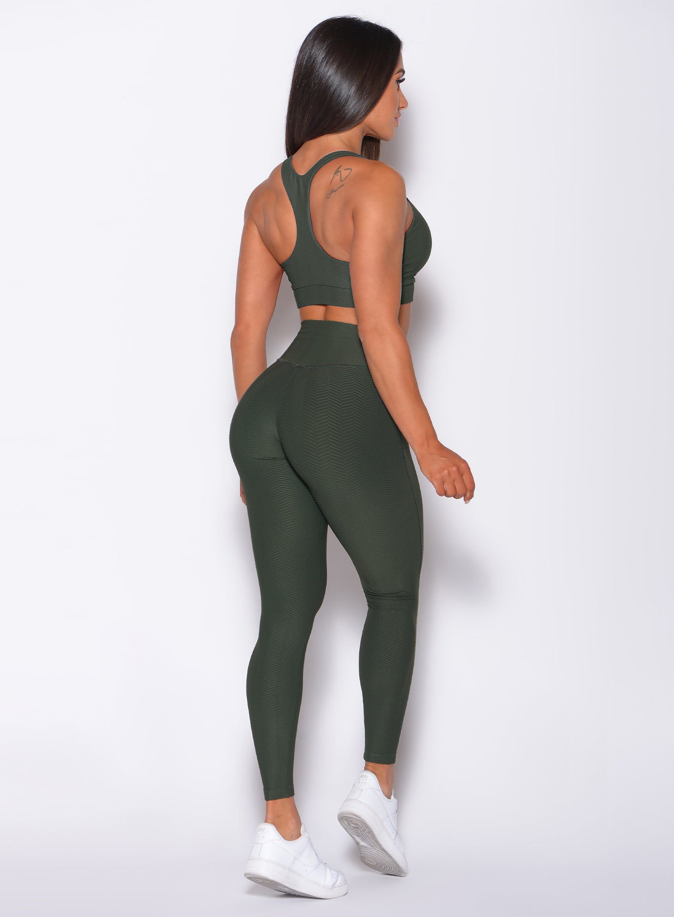 Back profile view of a model in our Chevron Leggings in lucky green color and matching bra