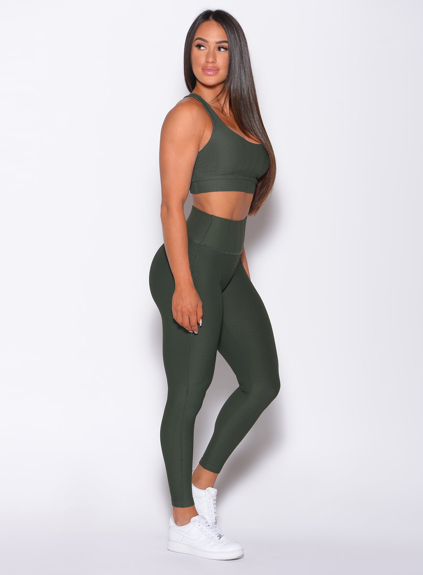 Right side profile view of a model in our Chevron Leggings in lucky green color and matching bra