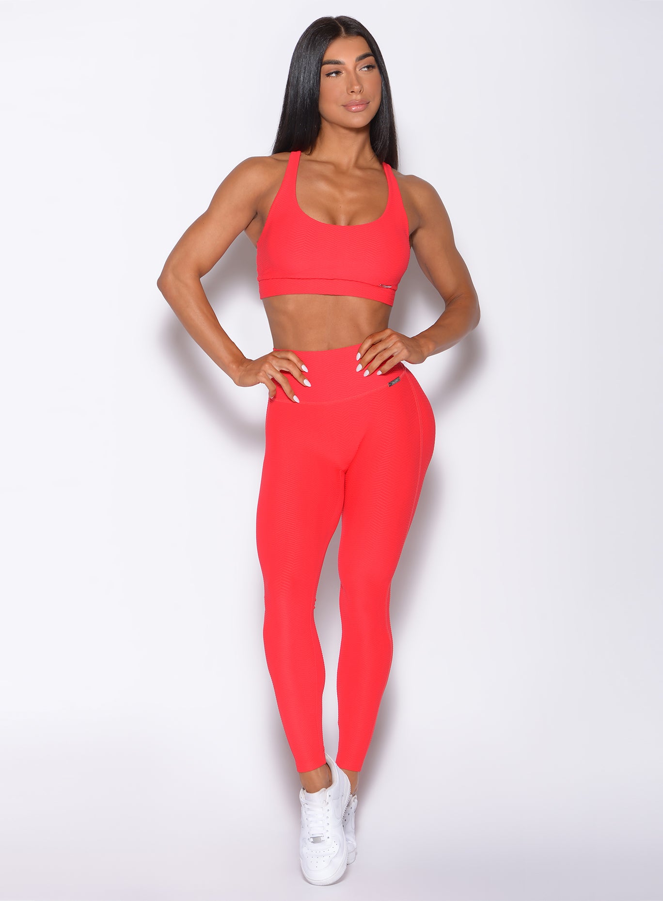 Back profile view of a model wearing our chevron sports bra in flame red color and a matching leggings