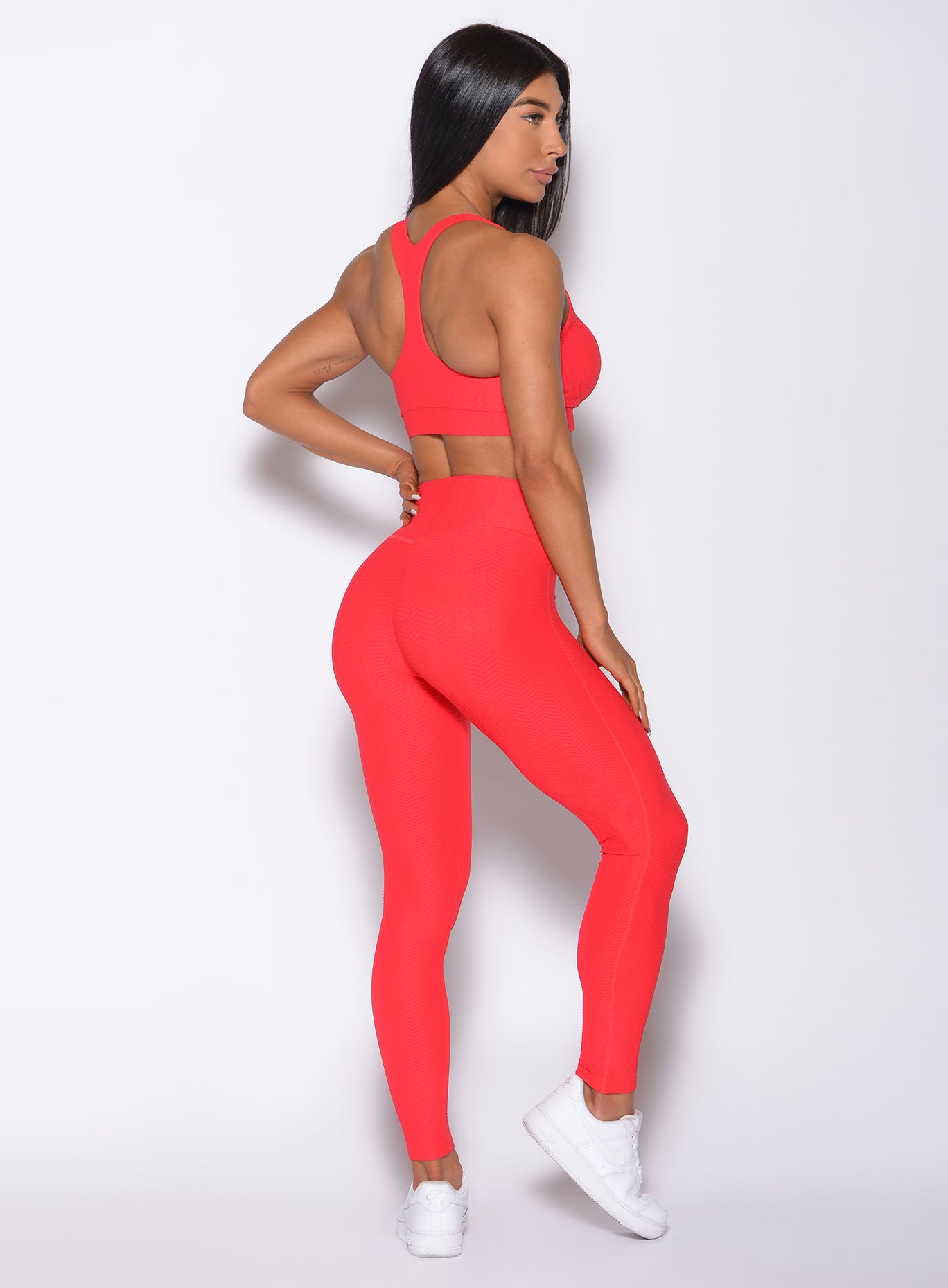 Right side profile view of a model in our Chevron Leggings in flame red color and matching bra