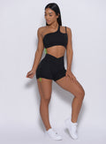 front profile view of a model looking to her right wearing our Contour Toggle Shorts in Black color and a matching sports bra