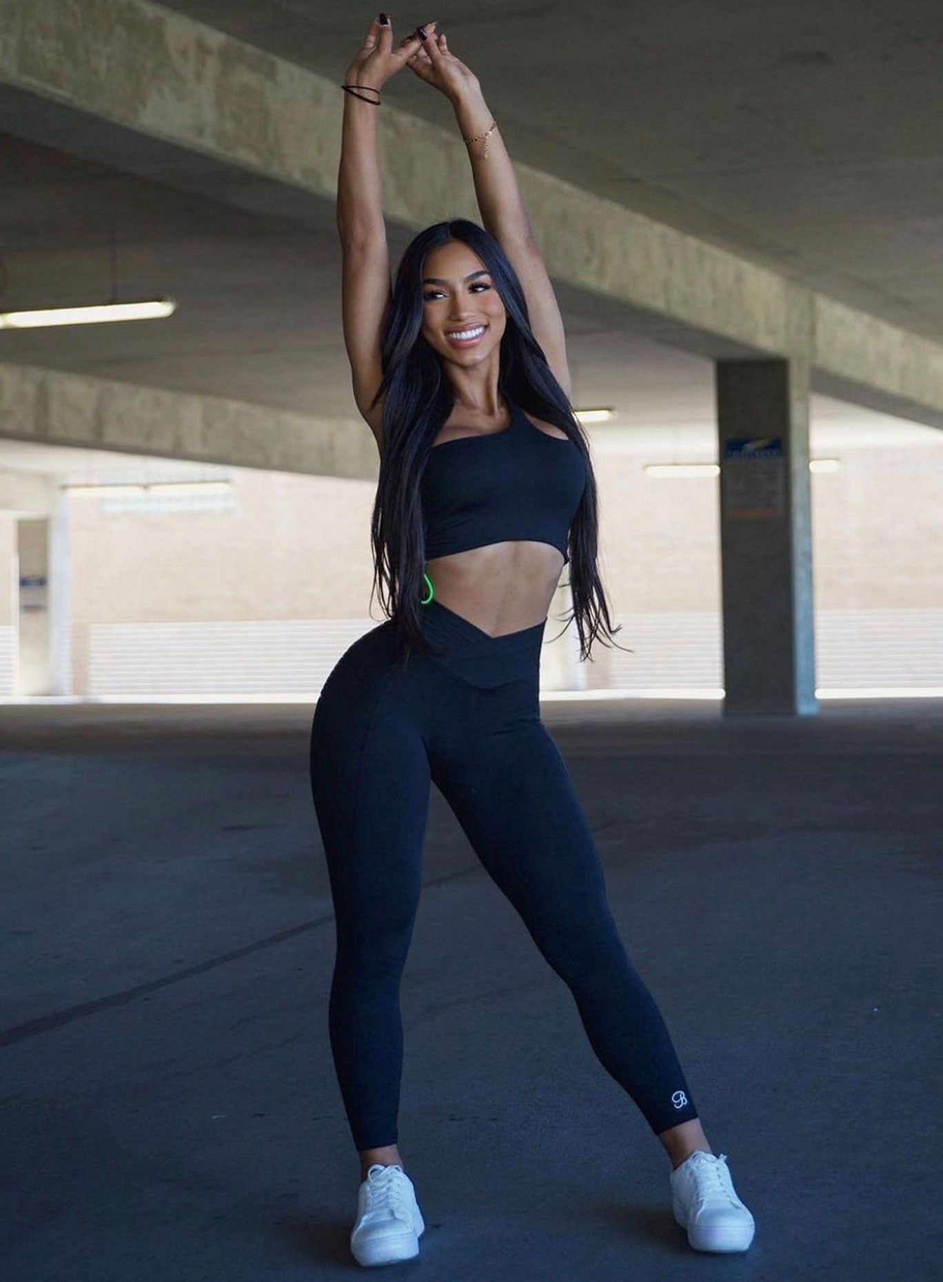 model in black contour leggings with arms up in the air over her head